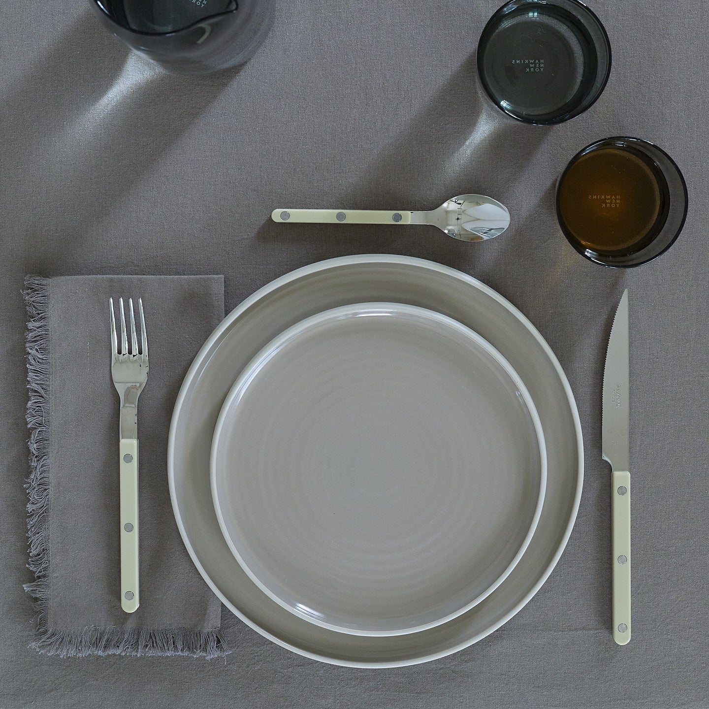 Placesetting with Essential Salad Plate in Light Grey on grey tablecloth.