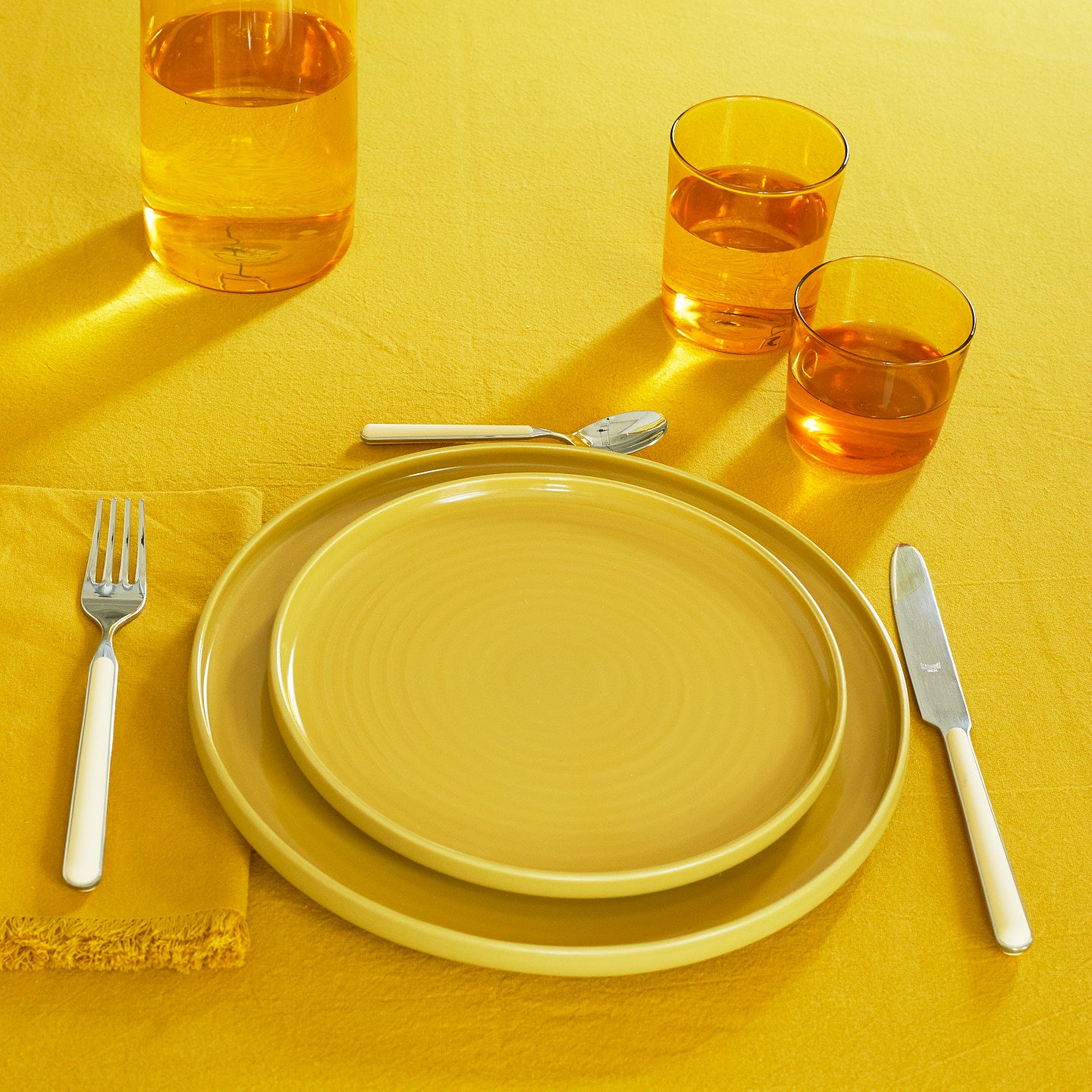 Placesetting with Essential Glassware in Amber on yellow tablecloth.