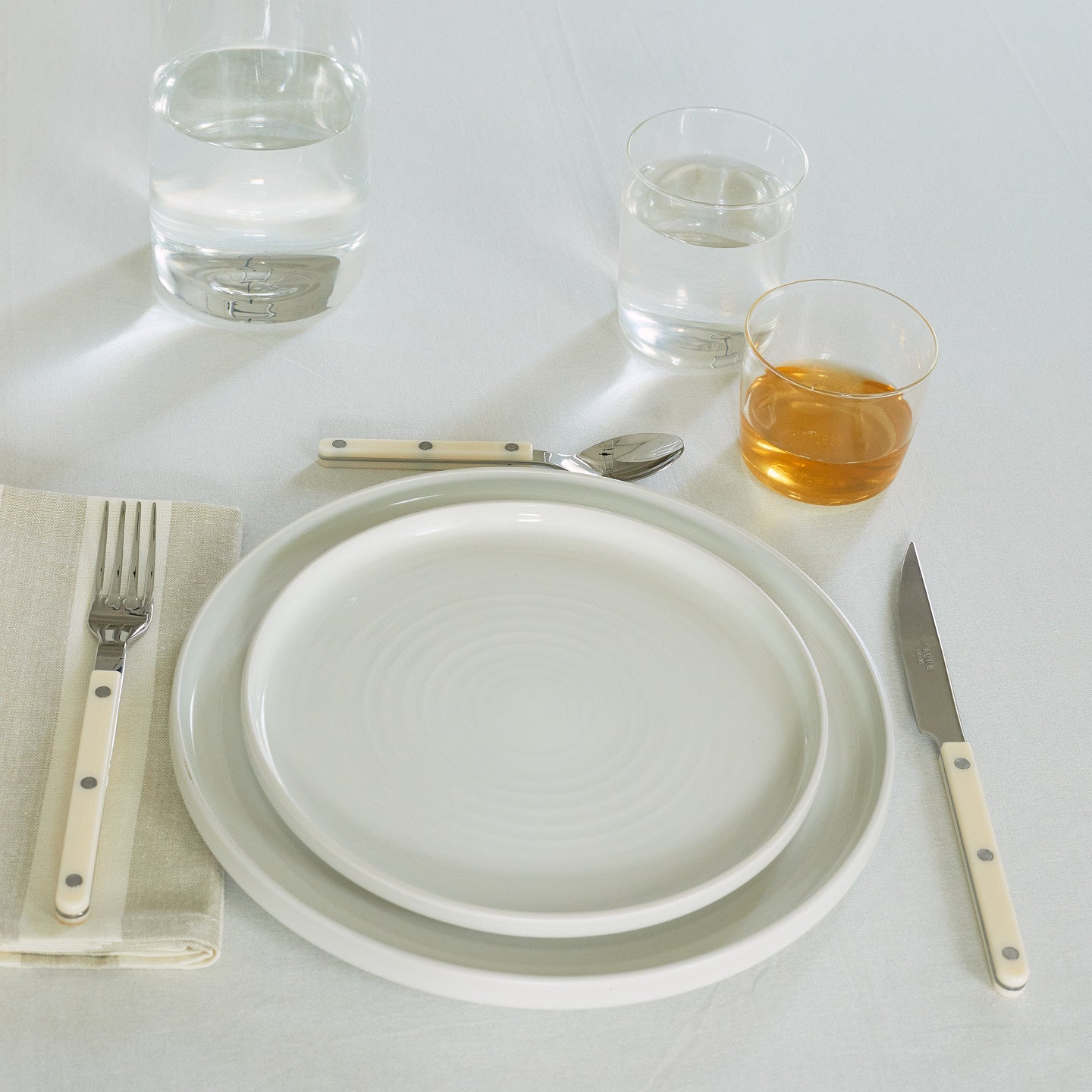 Placesetting with Essential Glassware in Clear on ivory tablecloth.