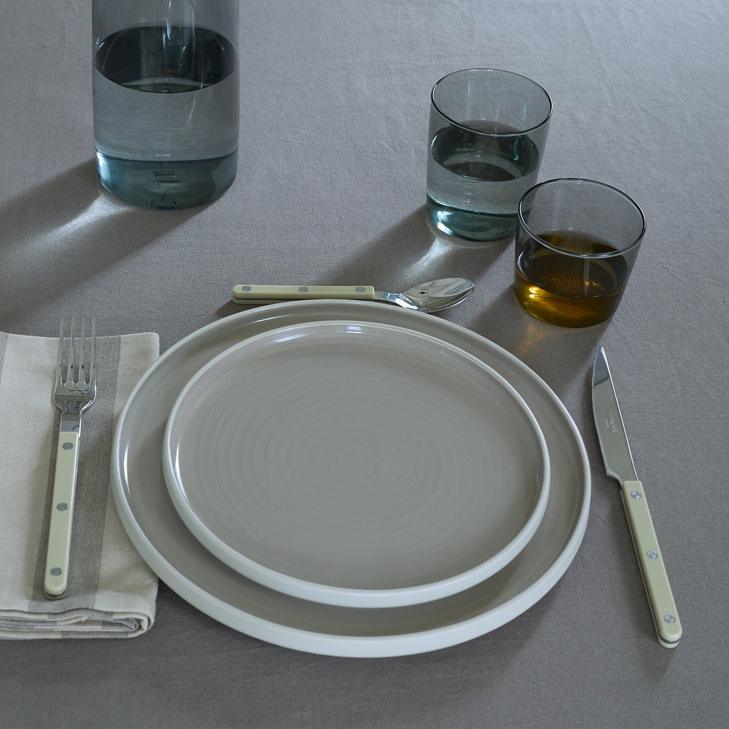 Placesetting with Essential Glassware in Smoke on grey tablecloth.