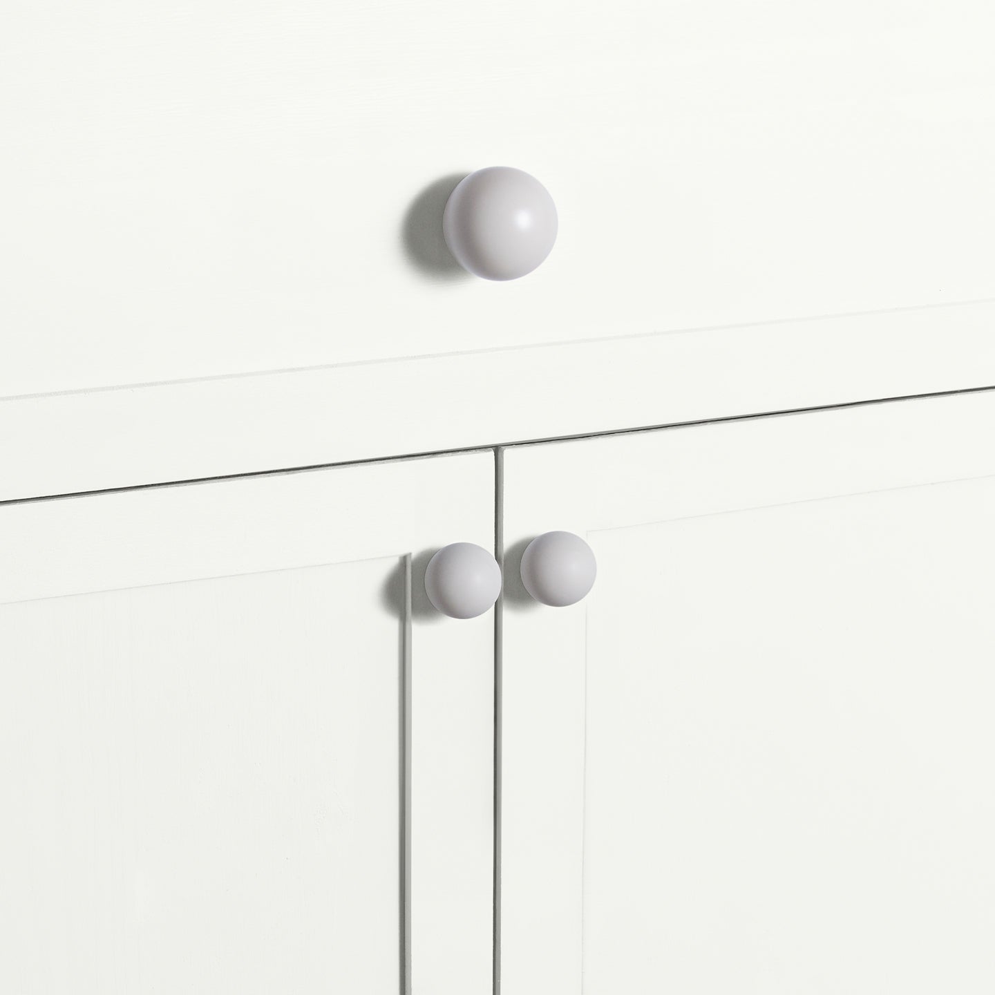 Large and small ivory essential sphere knobs on white drawers and cabinets