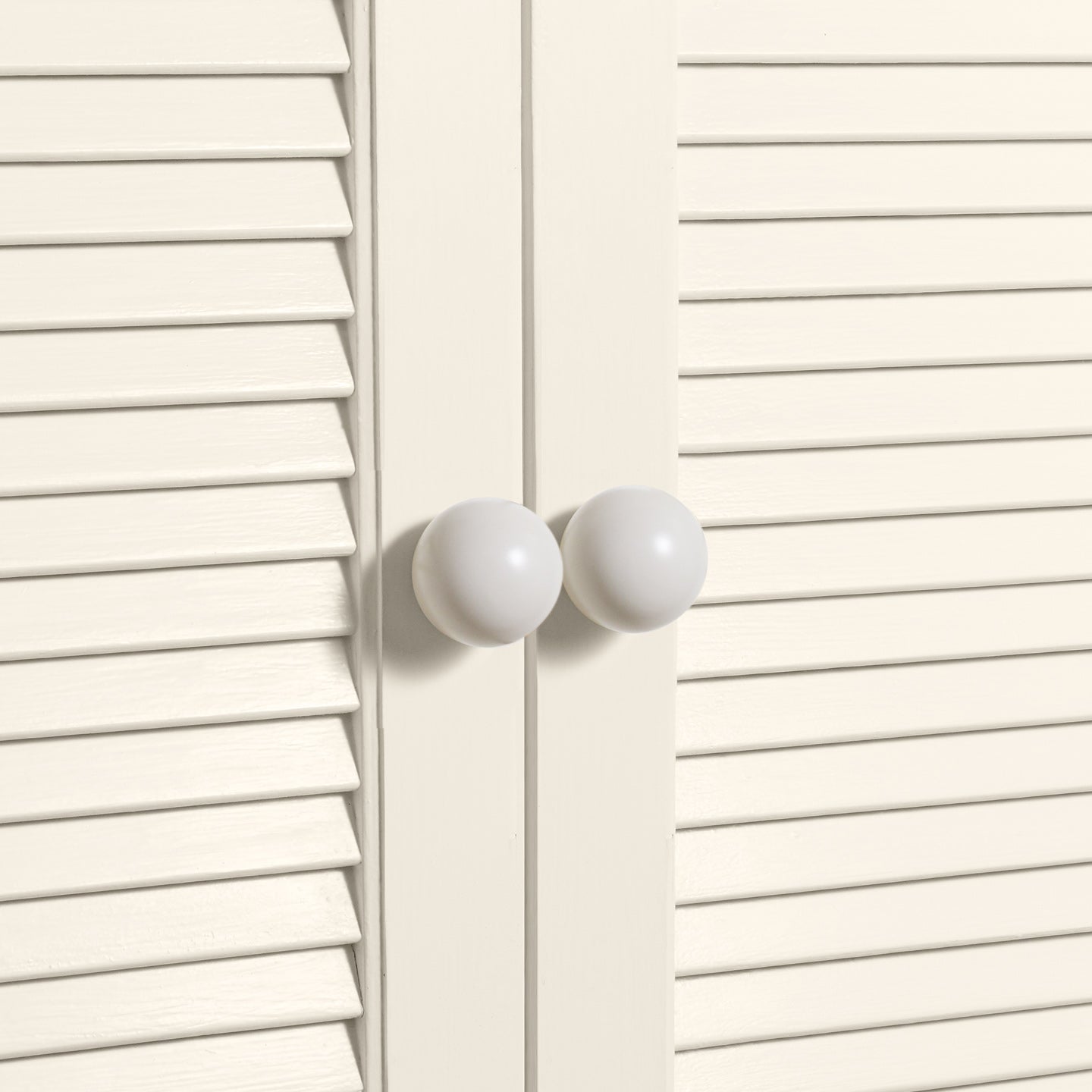 Large ivory essential sphere knobs on louvered doors