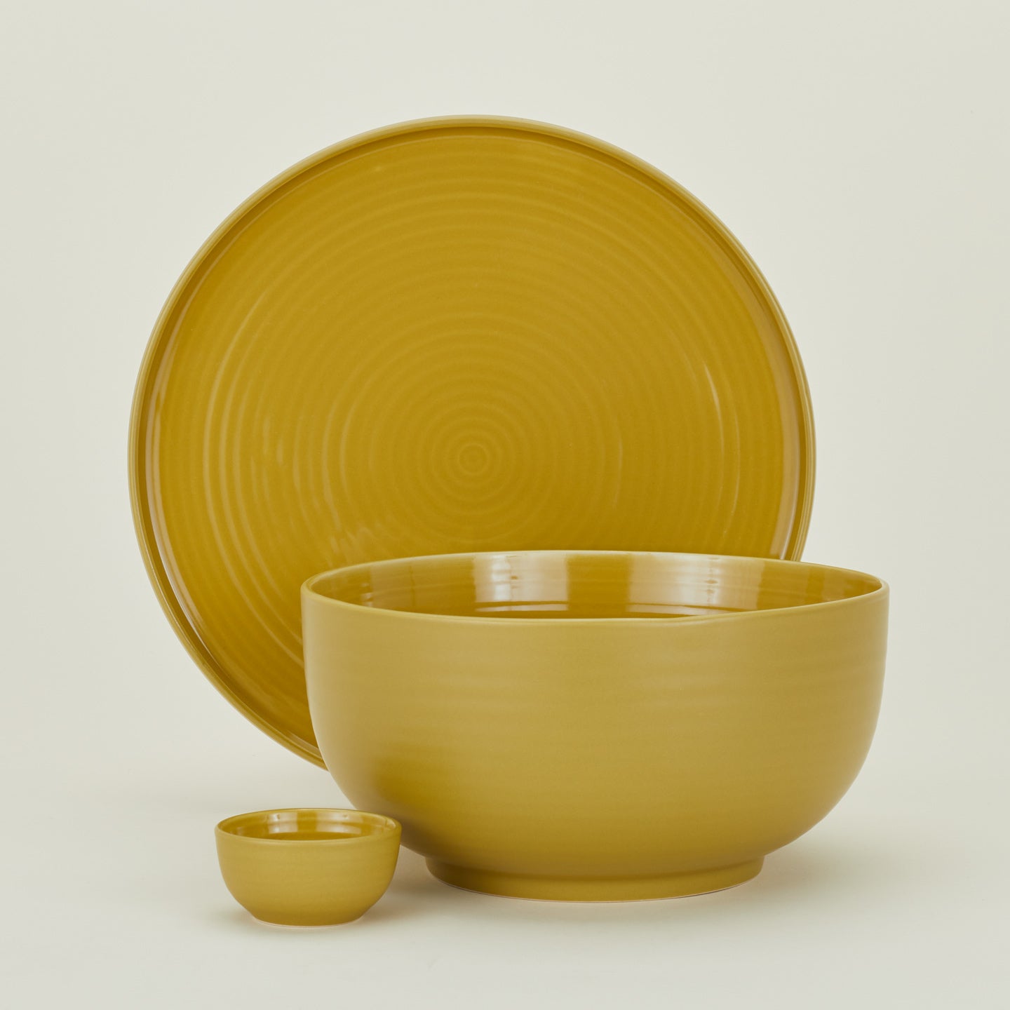 Group of Essential serving pieces in Mustard including bowl, platter and extra small bowl.