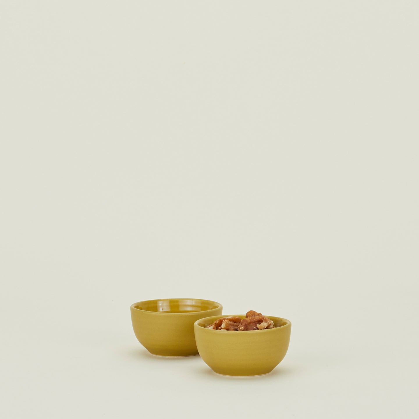 Two Essential Extra Small Bowls in Mustard filled with nuts.