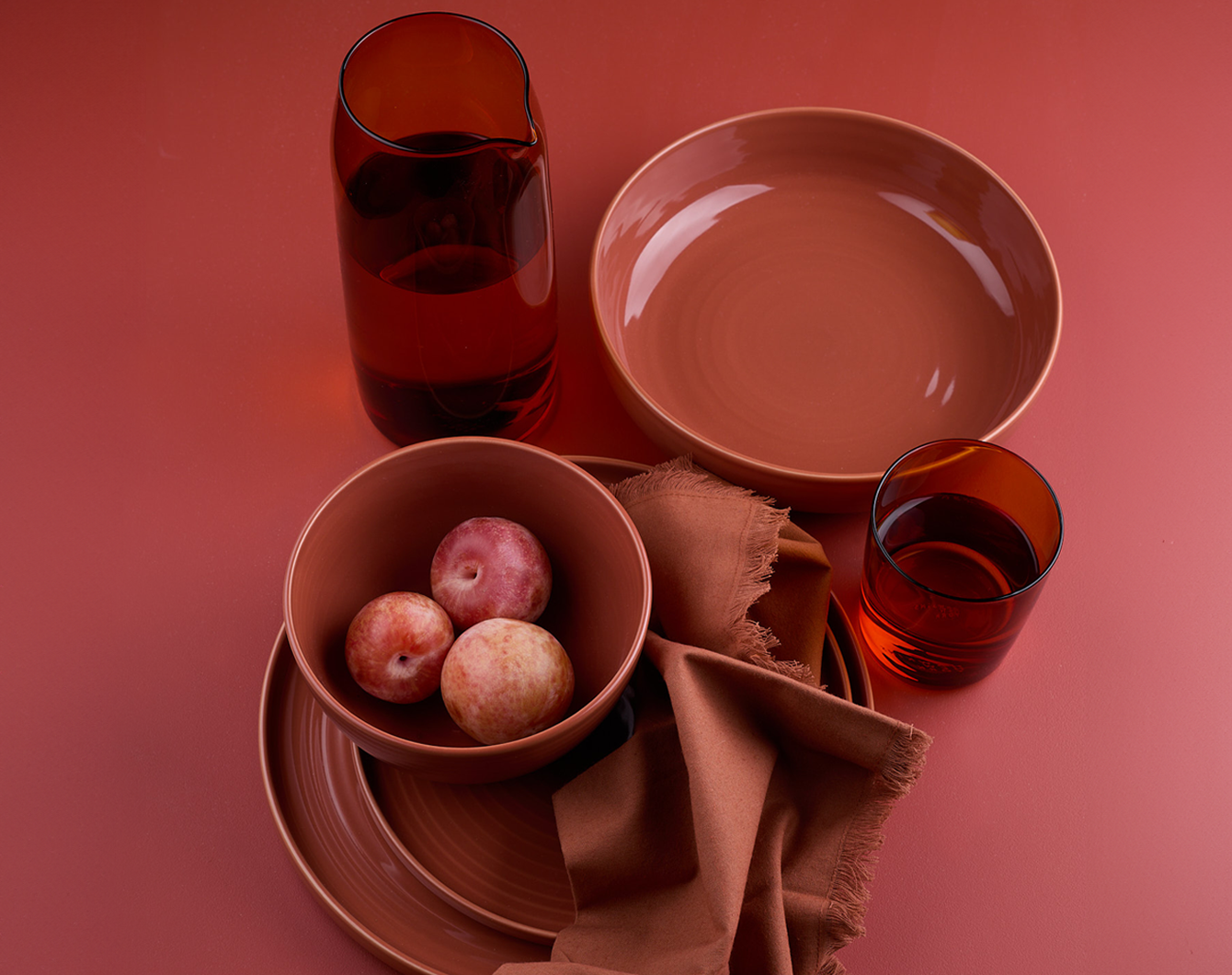 Essential dinnerware, glassware, pitcher, and napkins in Terracotta tones.