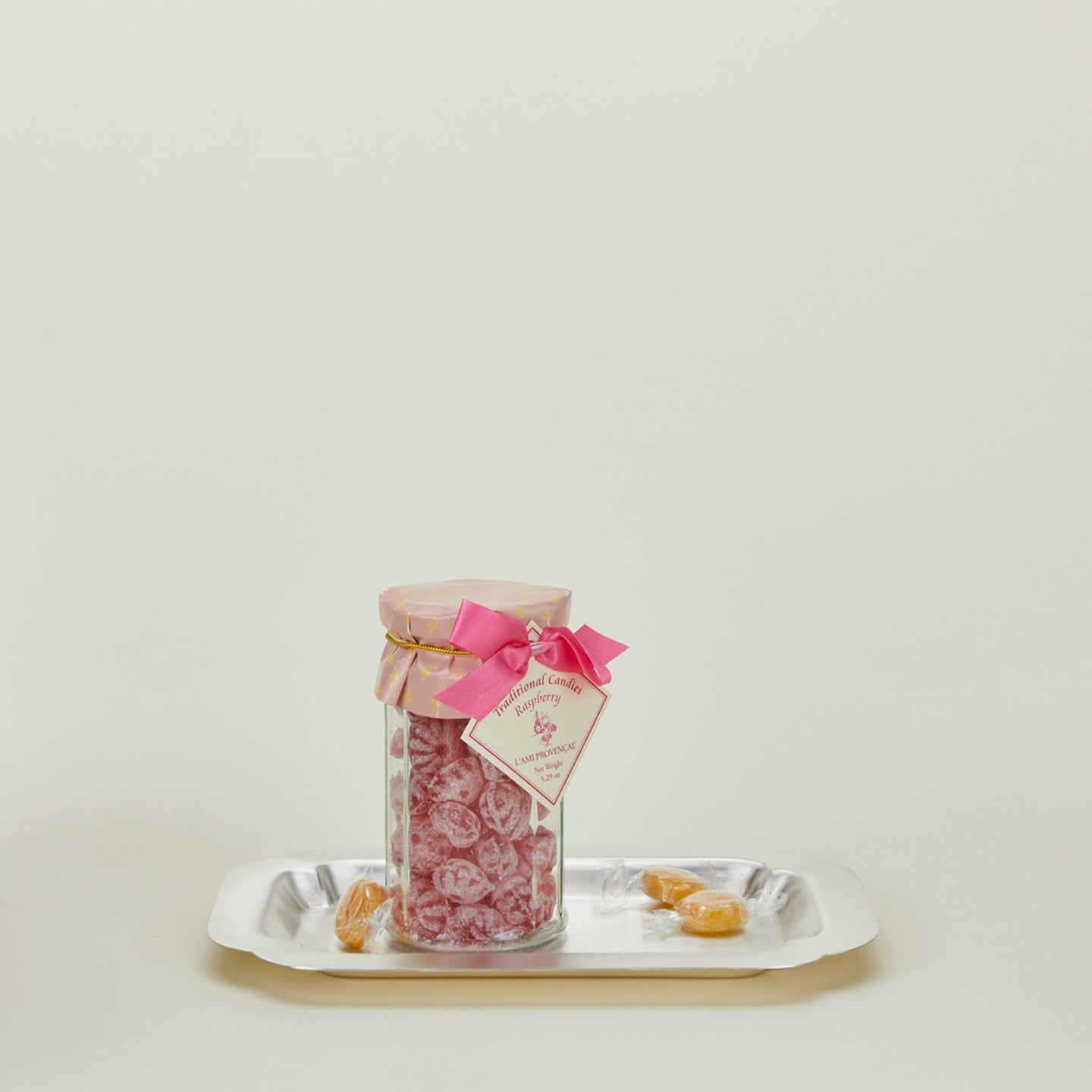 Decorative edge silver platter with jar of traditional raspberry candies and butterscotch candies at base 