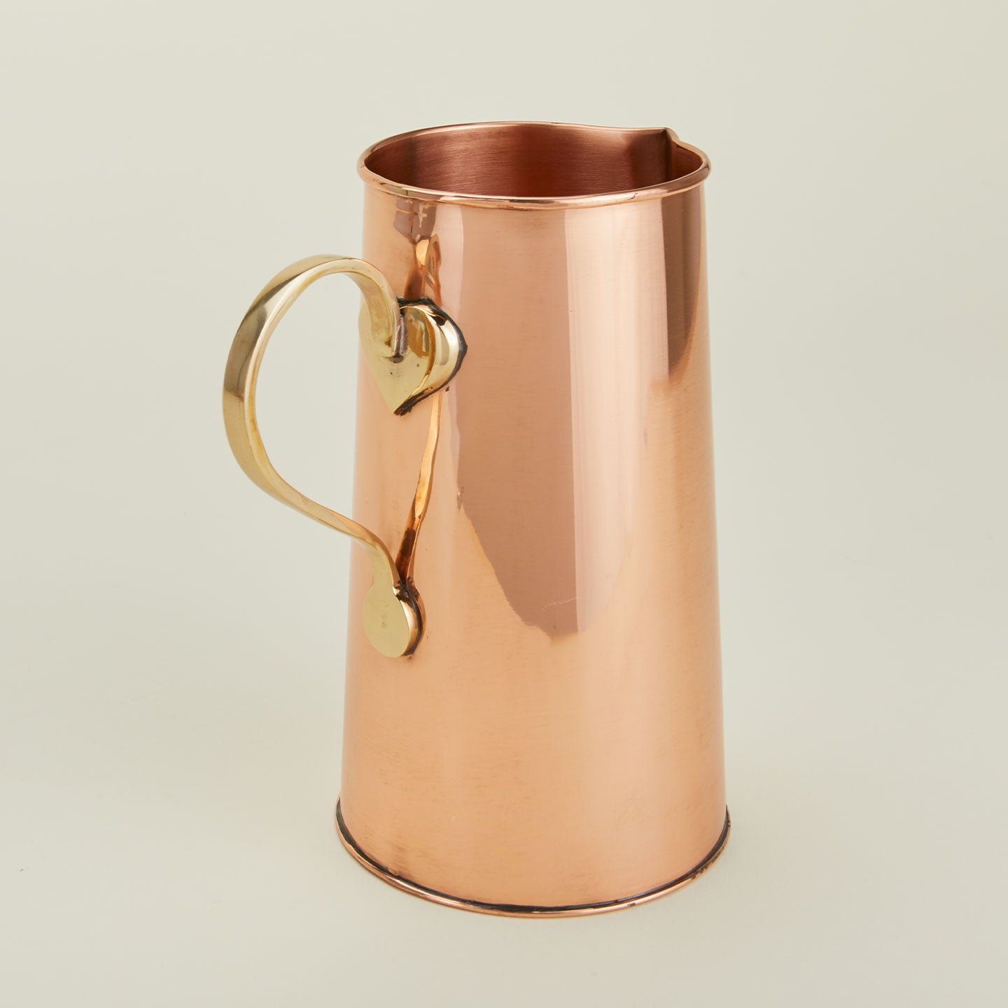 Close up of copper water pitcher with brass handle.