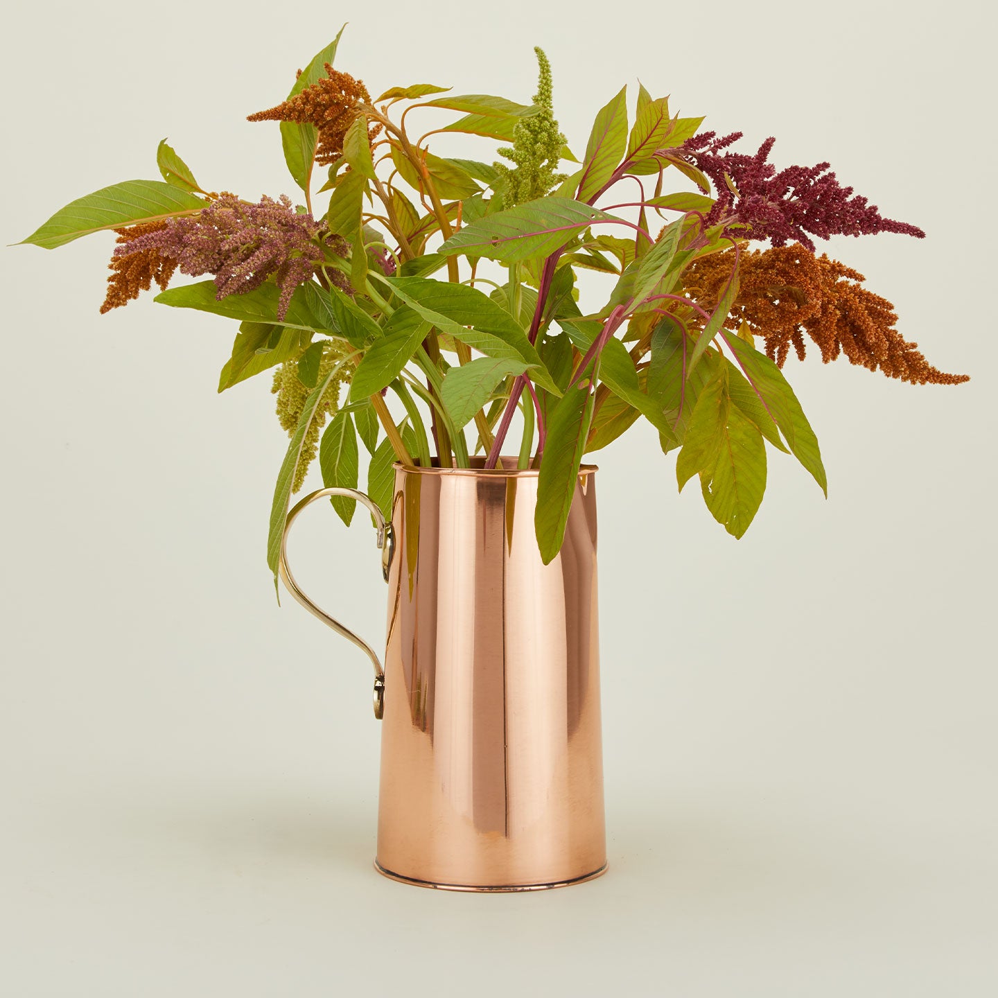 Copper water pitcher with brass handle and florals.