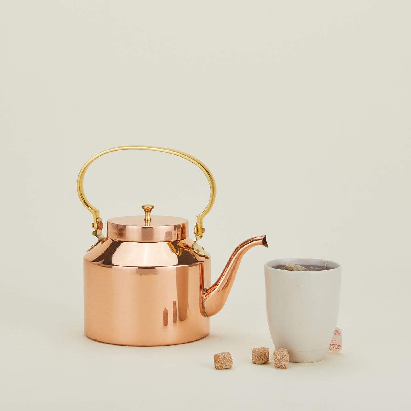 English copper tea kettle with brass handle and mug with tea.