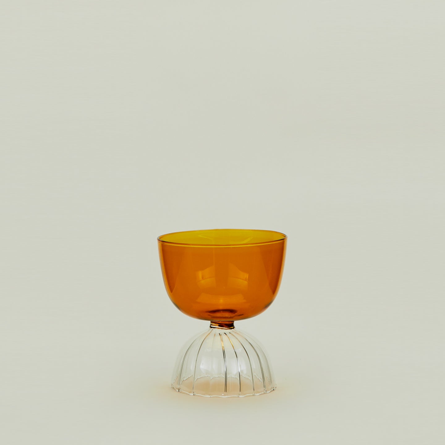 Drinking glass with clear stem and amber cup, filled with ice water.
