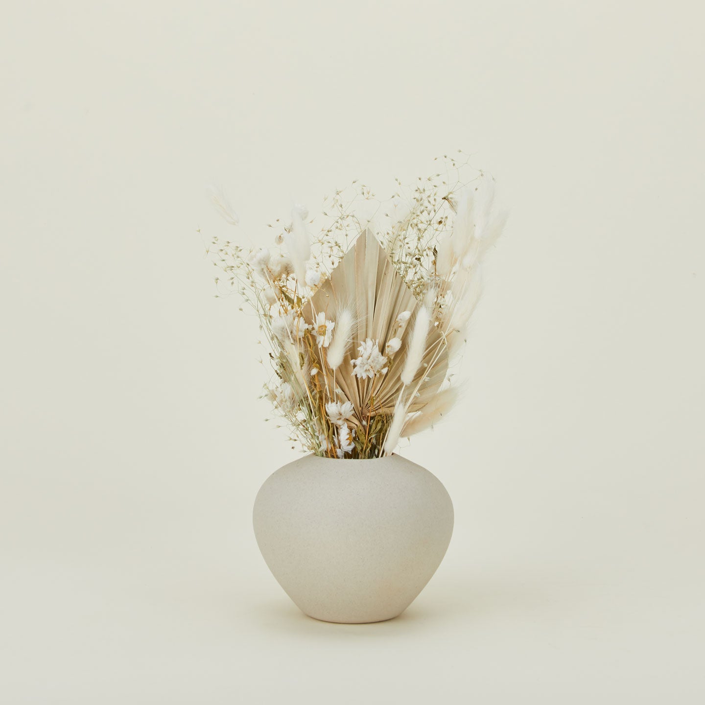 Dried floral bouquet in neutral colors in a vase.