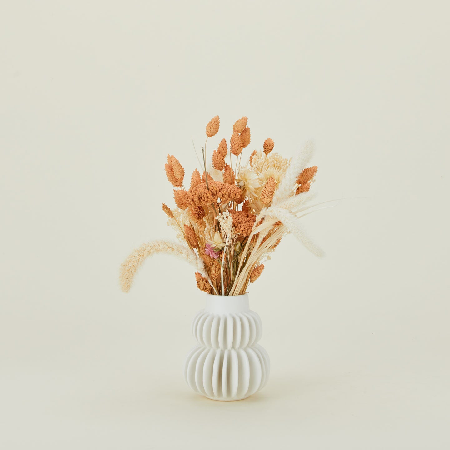 Dried floral bouquet in peaches and cream in a vase.