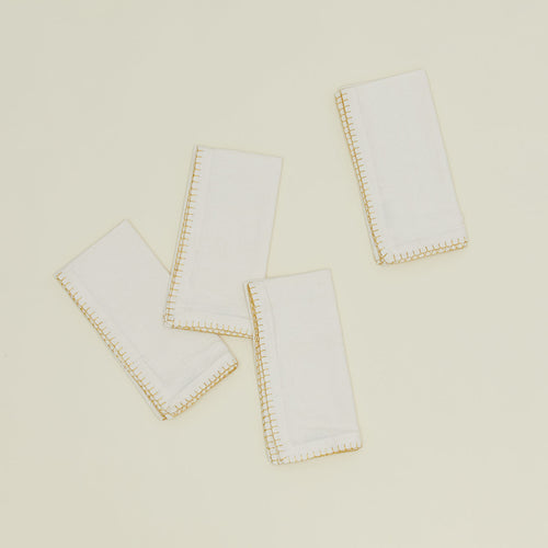 A set of four ivory napkins with gold blanket stitching. 