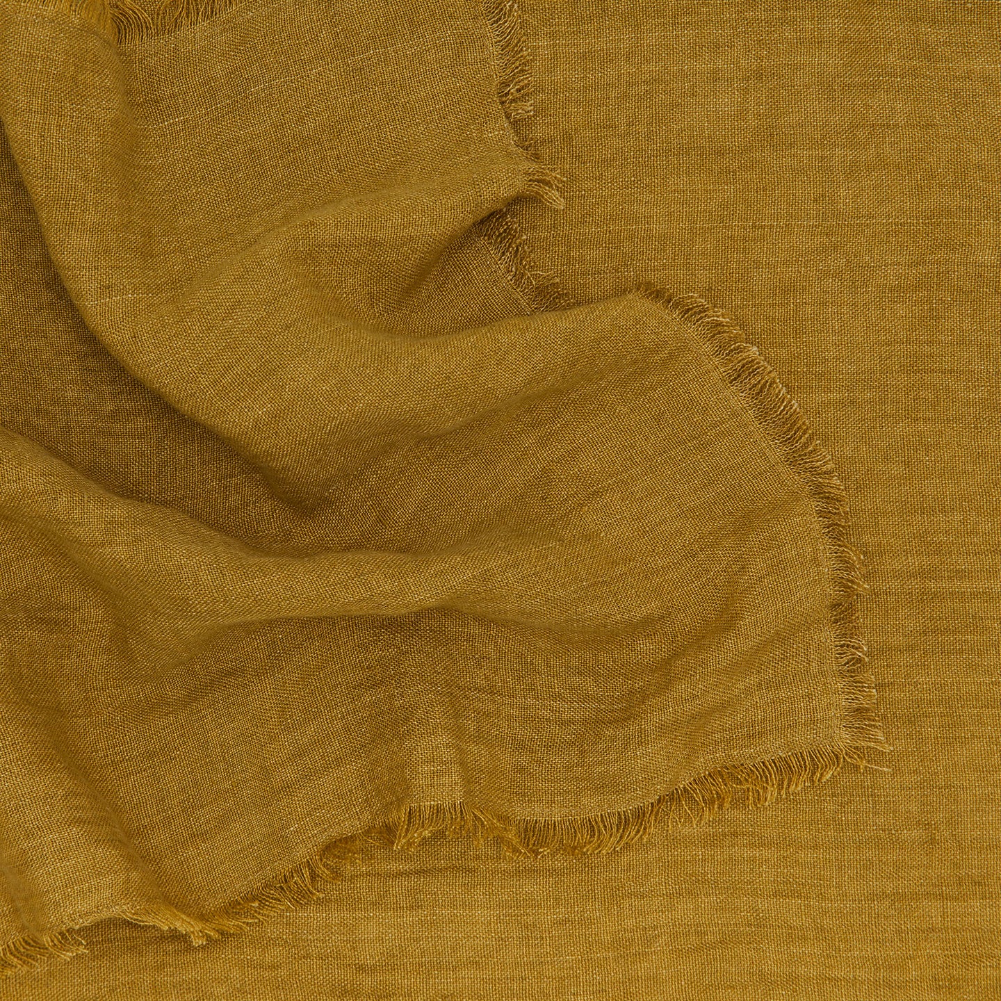 Close up of a linen runner with frayed edge in bronze.