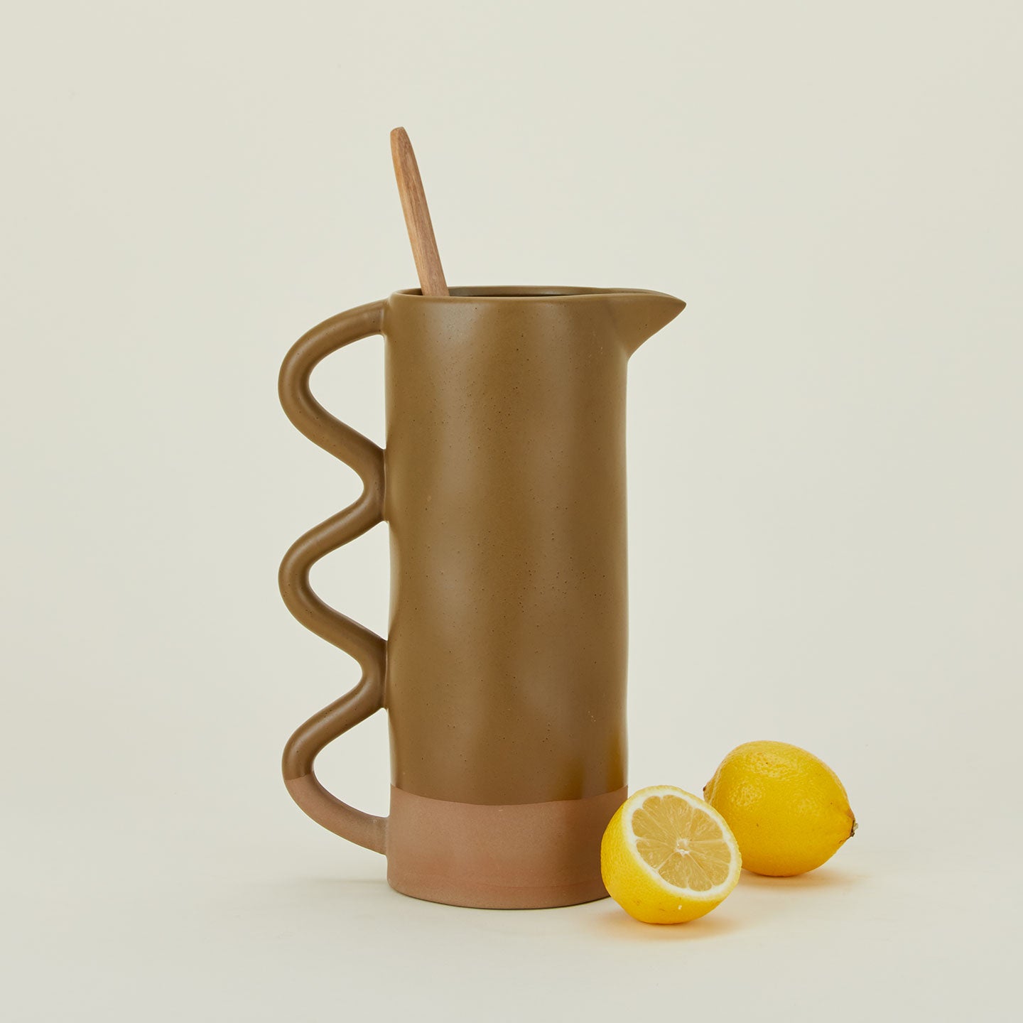 Stoneware pitcher with wavy handle in bronze with lemons and stirrer.