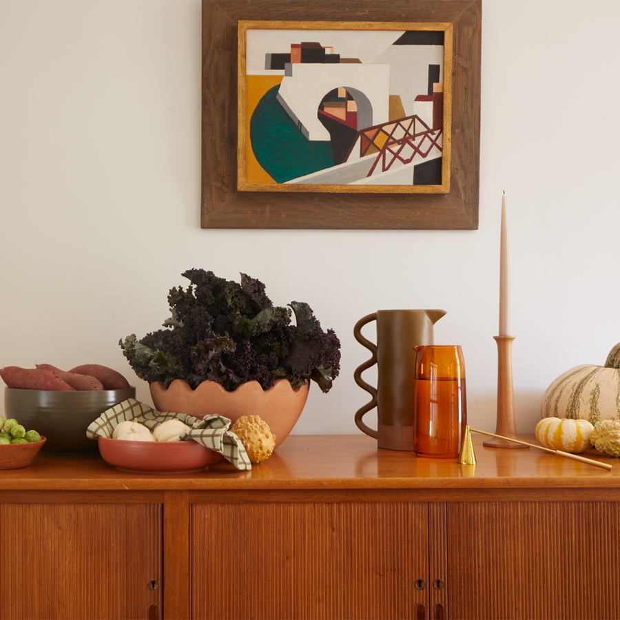 Sideboard with artwork hung on wall. and various bowls and pottery