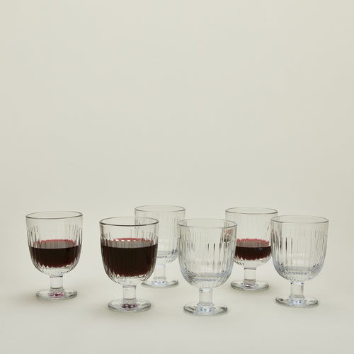Six Ouessant wine glasses, some with wine.