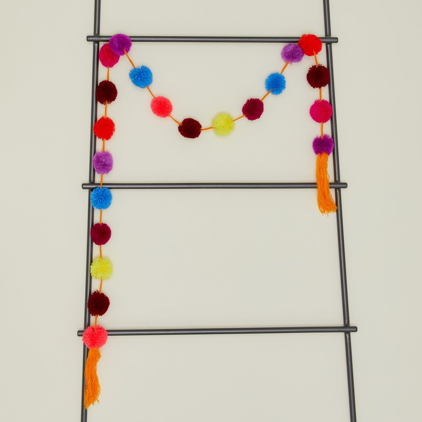 Magic pom pom garland in multicolor flash on ladder