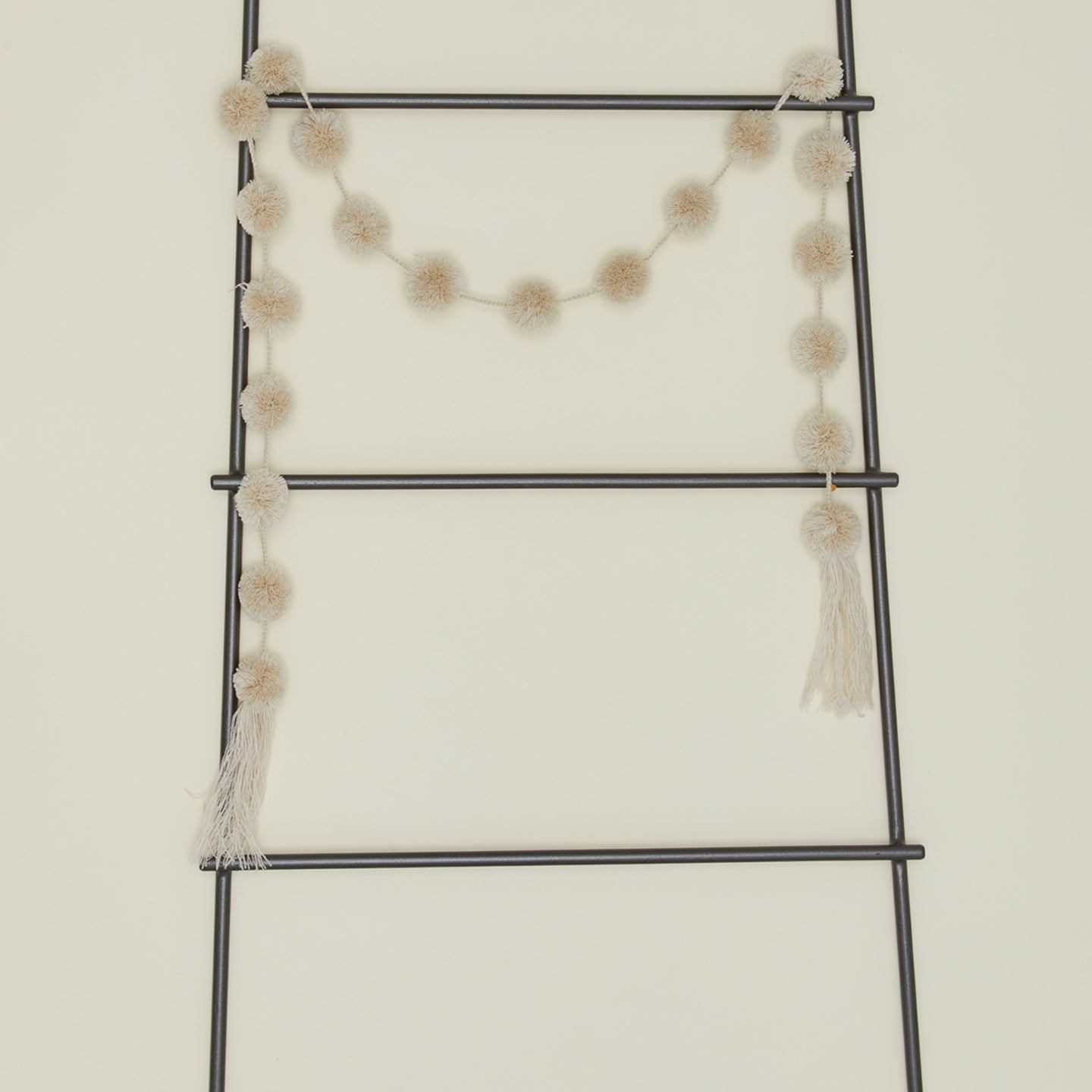 Magic pom pom garland in sand on ladder