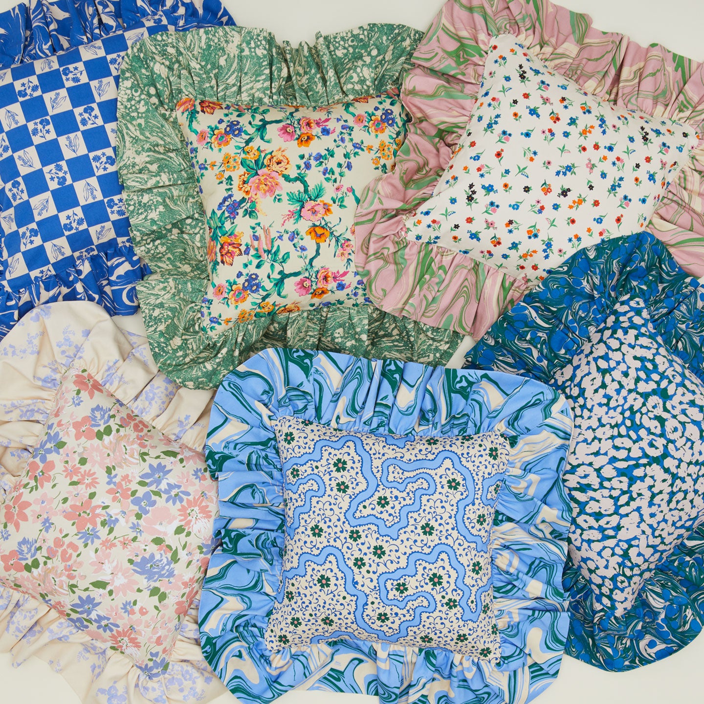 Six patterned ruffled floral cushions.