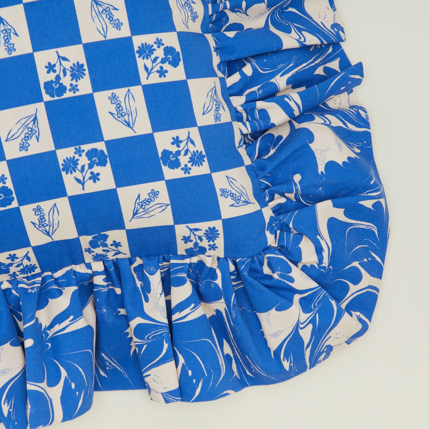 A close up of a ruffled floral cushion with a klein blue pattern.