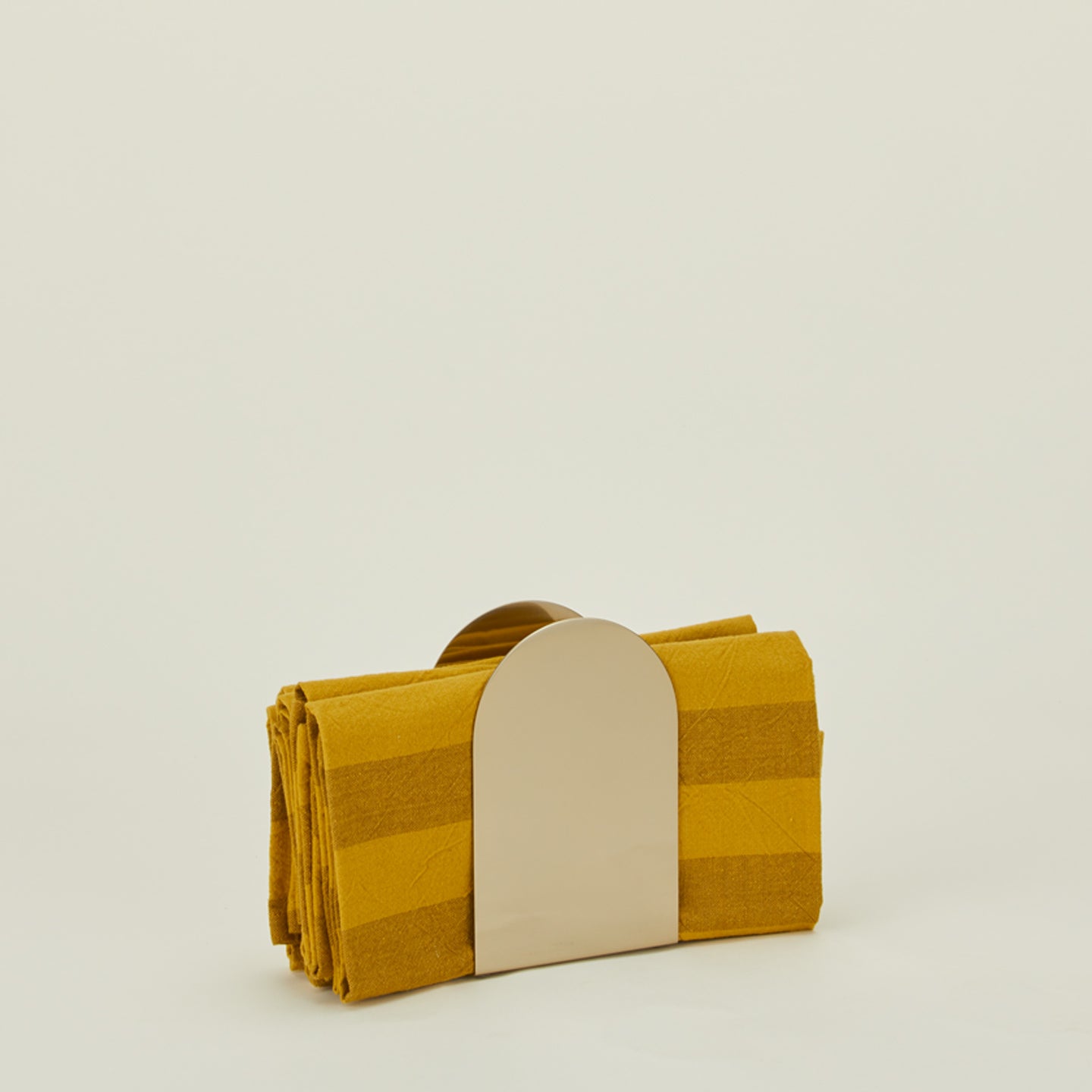 Arco brass napkin holder with mustard striped napkins. 