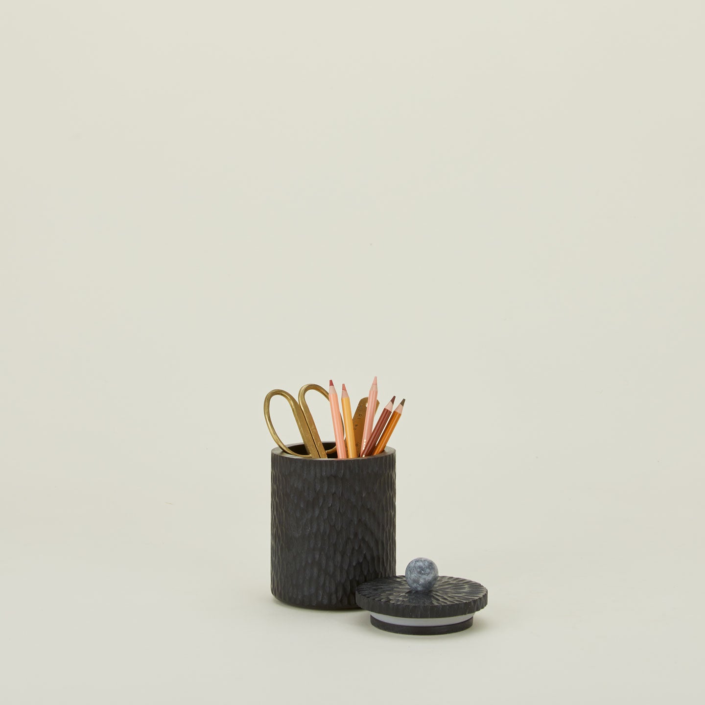 Small Camelia black wood lidded canister with marble knob, with office supplies.