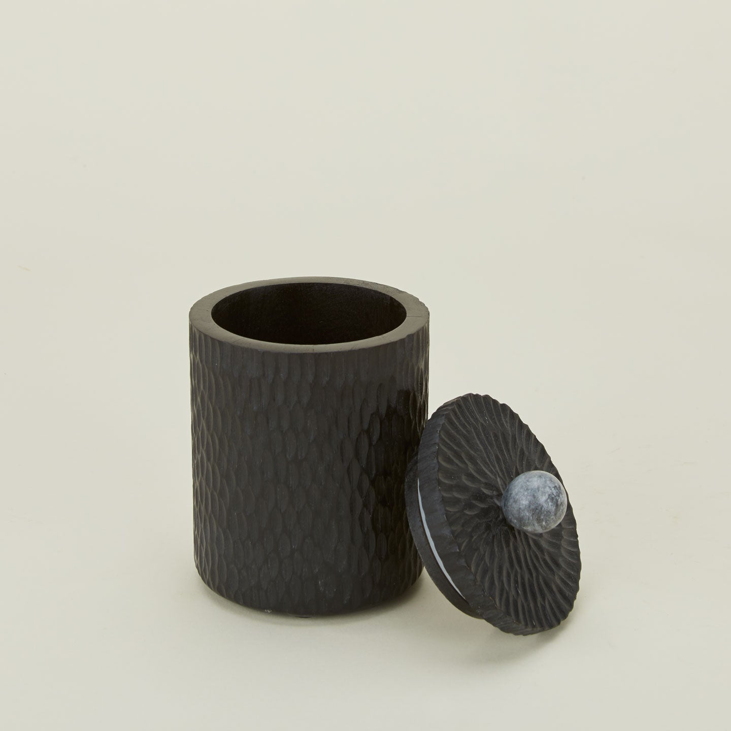 Close up of small Camelia black wood lidded canister with marble knob.