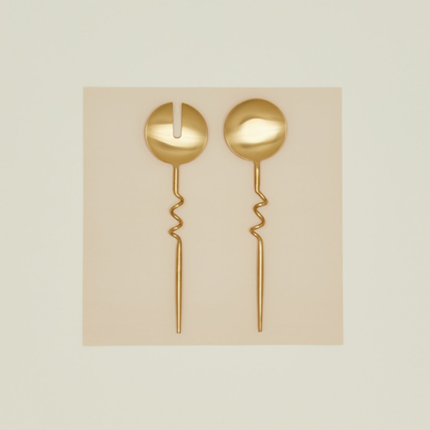 Set of two Elisa brass servers on paper background.