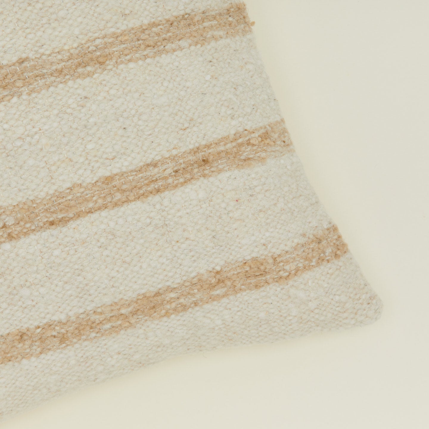 Corner detail of striped Linear wool pillow in tan and ivory.