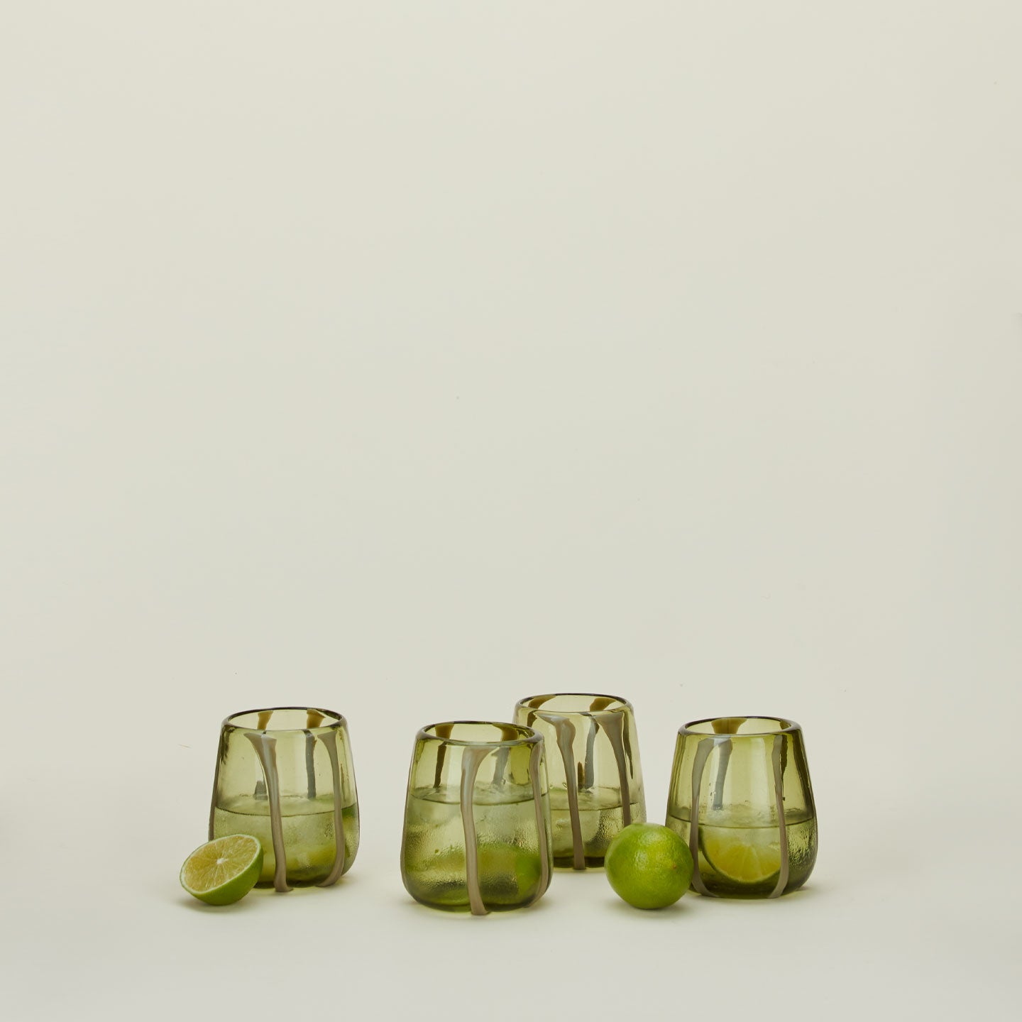 Set of four Olivia Green Olive Glasses with limes and ice.