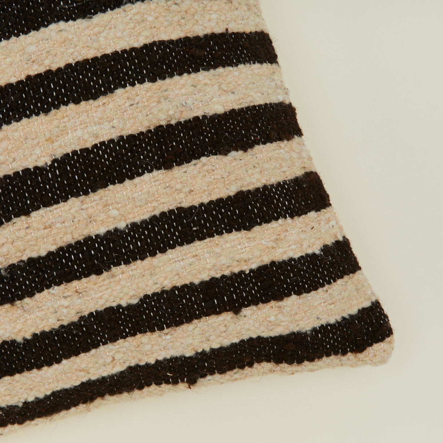 Corner detail of Striped wool pillow in black and tan.