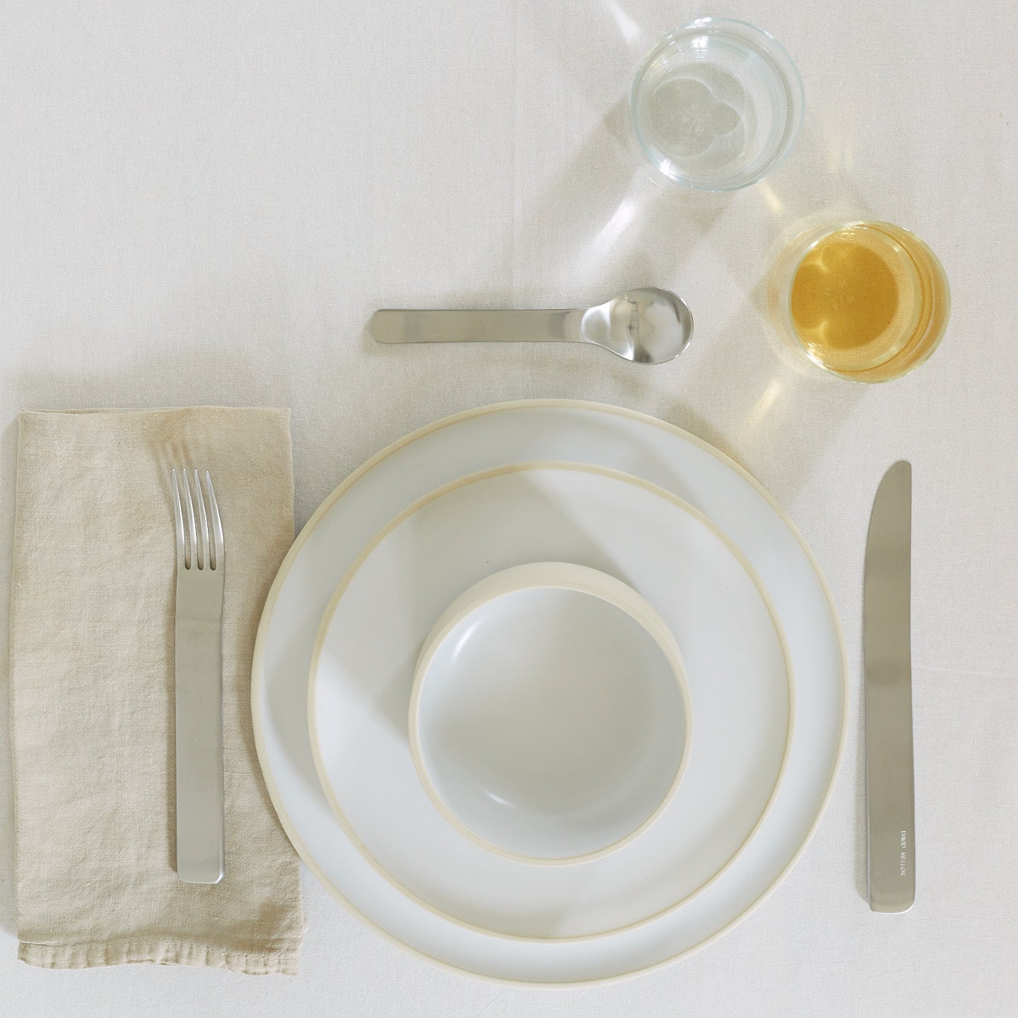 Placesetting with Modernist Salad Plate on ivory striped tablecloth.