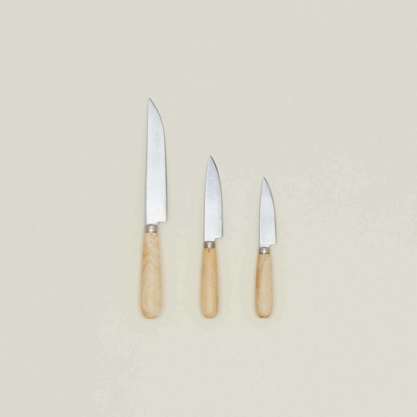 An overhead of three knives with wood handles in varying sizes.