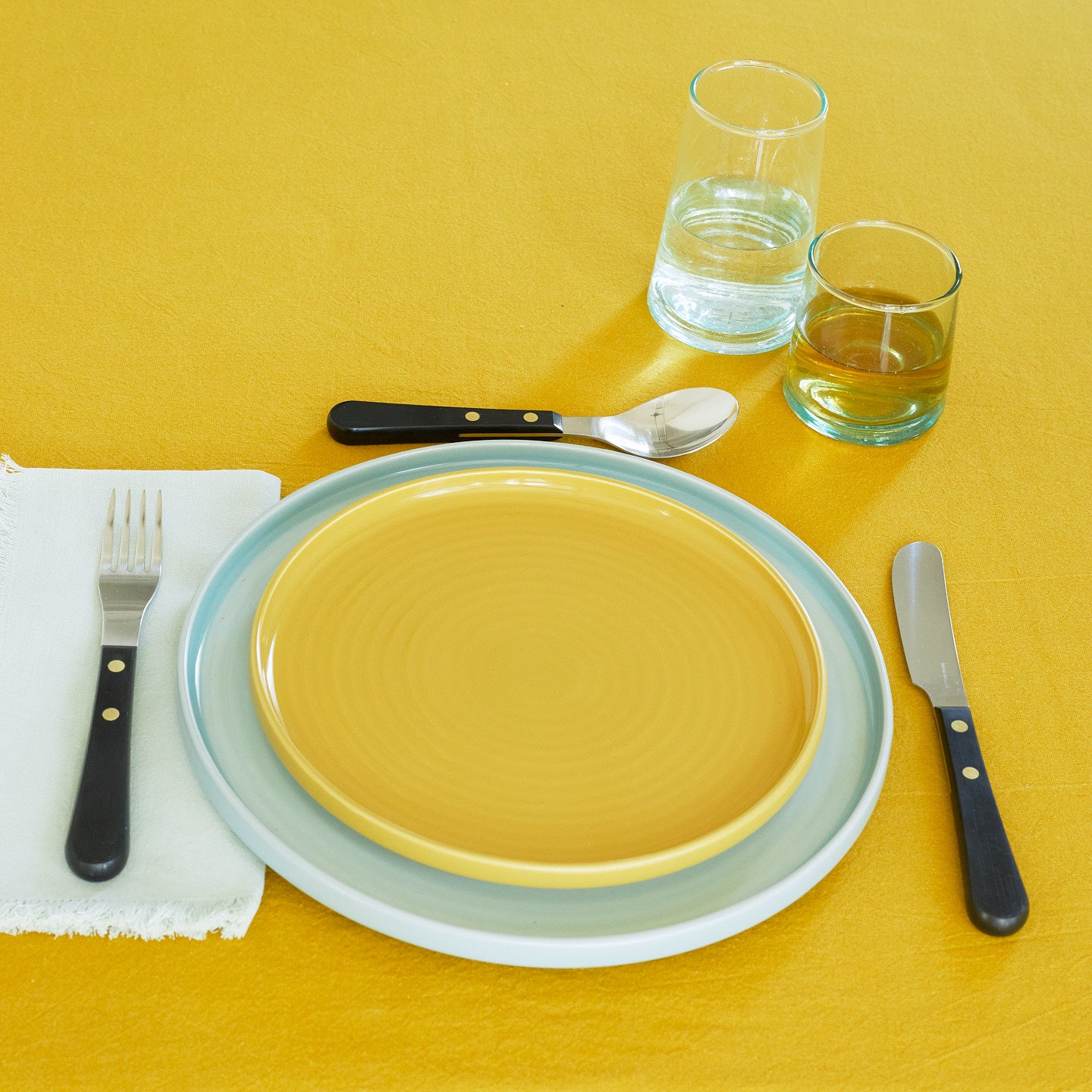 Placesetting with Recycled Glassware on yellow tablecloth.