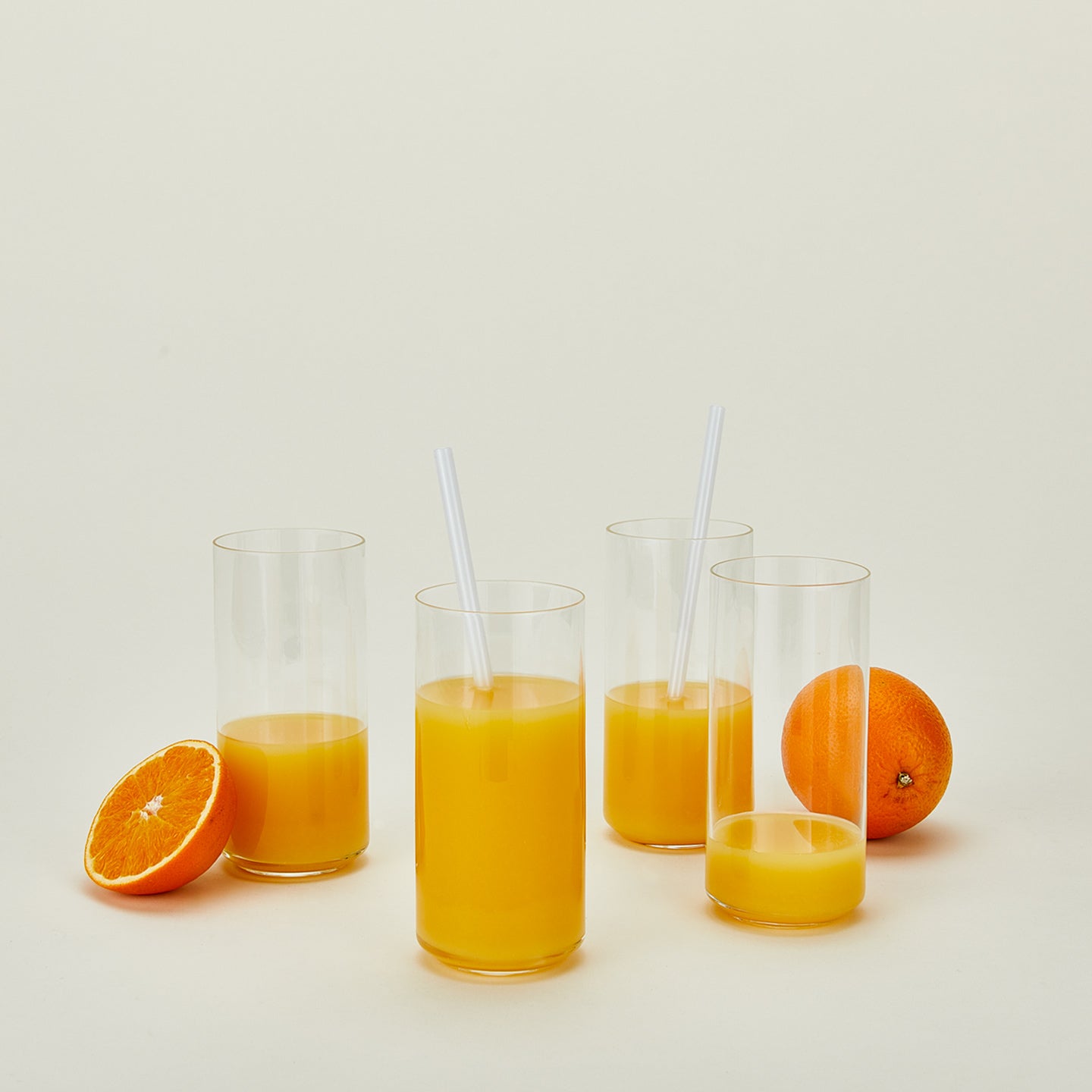 Simple glassware tall with oranges, orange juice and straws