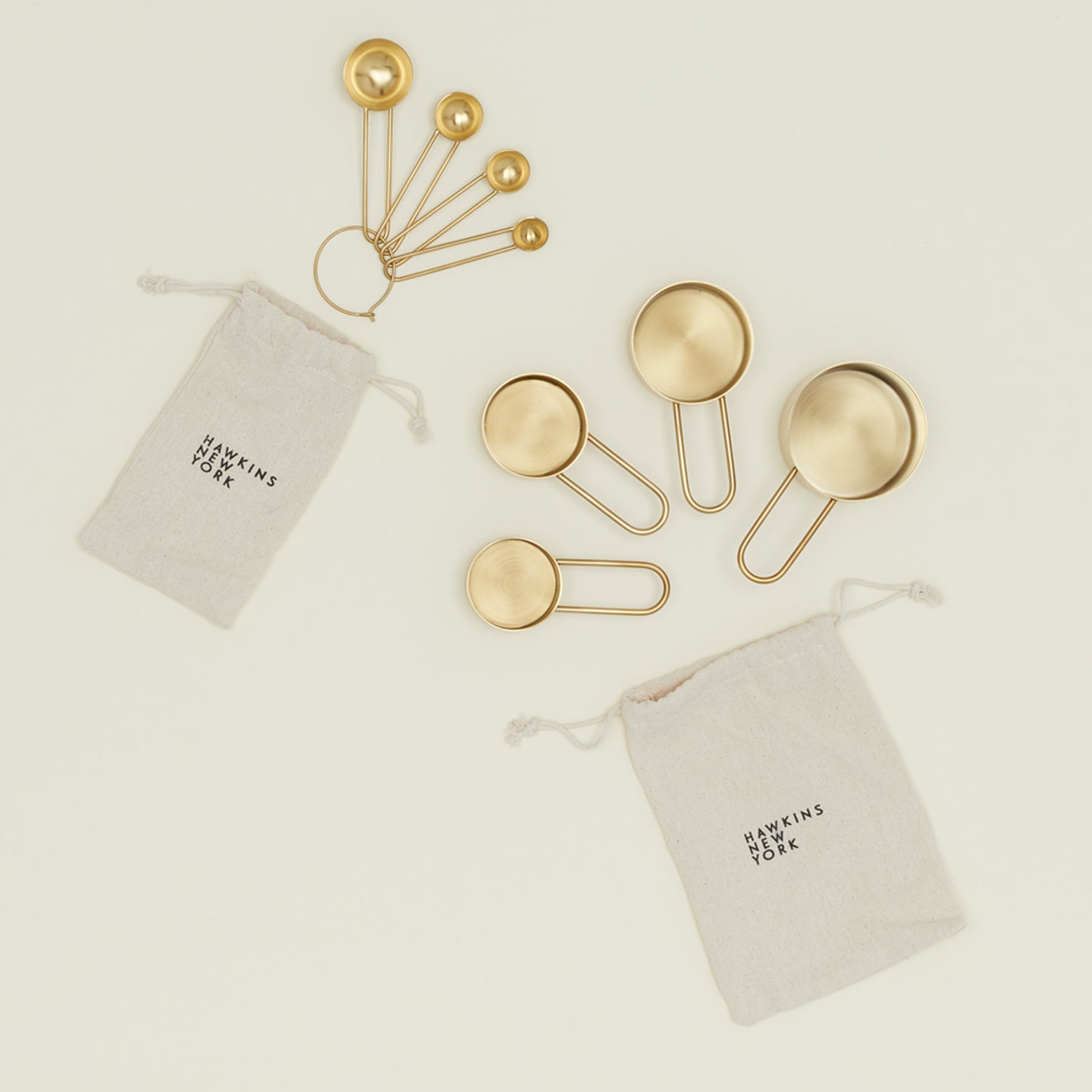 Simple measuring spoons and cups in brass with linen storage bags