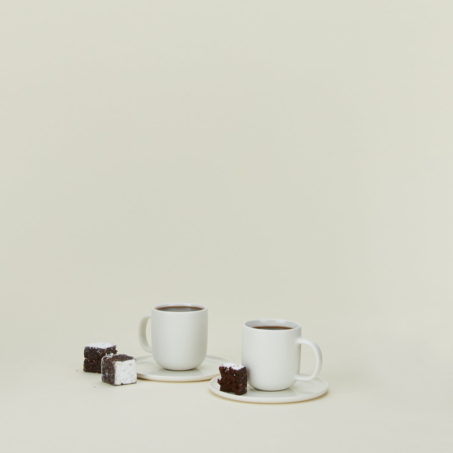 Simple porcelain espresso mugs with saucers in white with cake