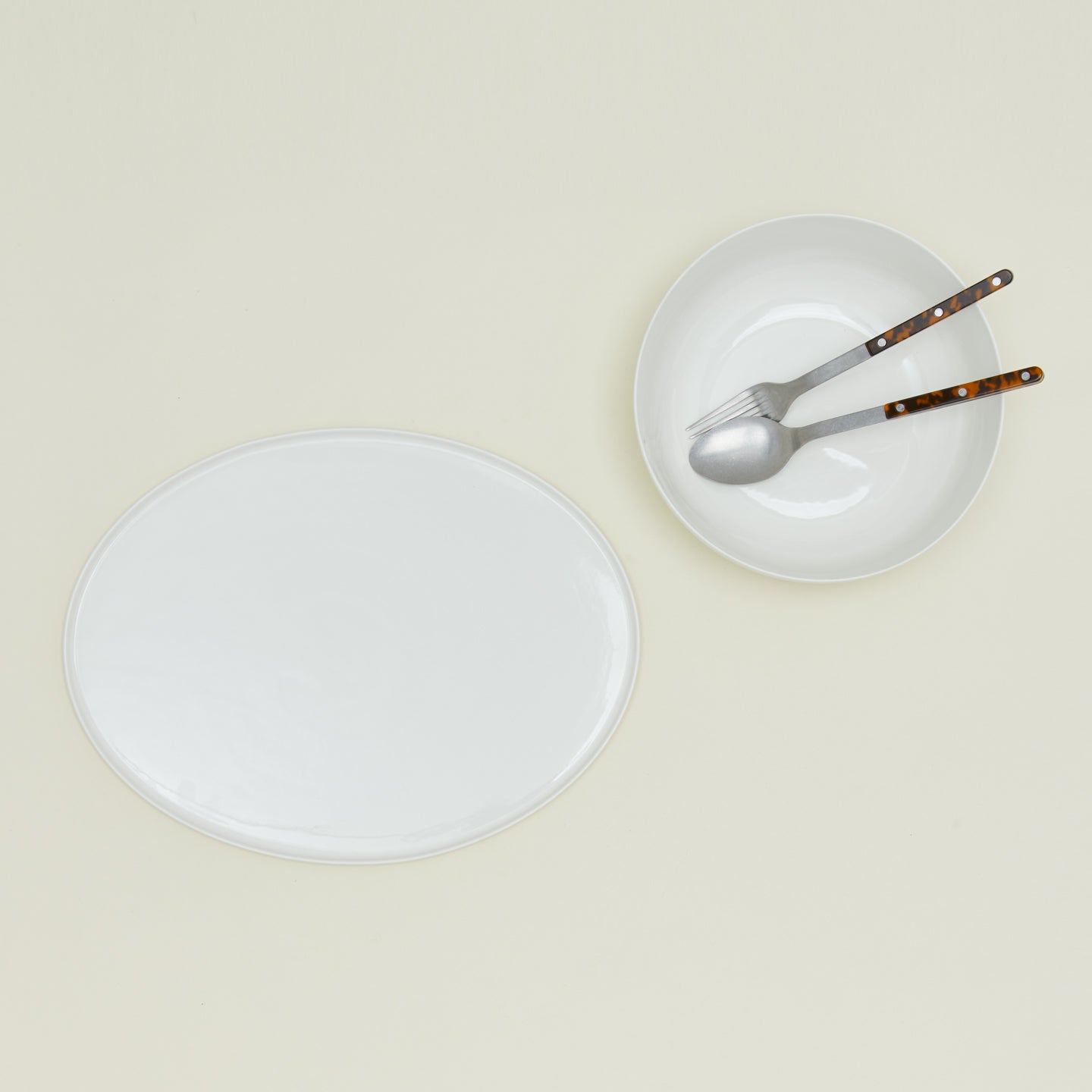 Simple porcelain serving platter and serving bowl in white with serving utensils