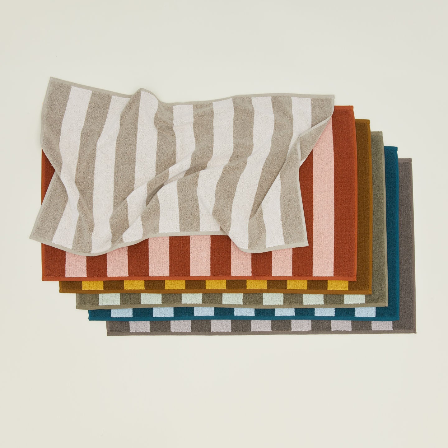 An overhead of six striped terry bath mats in various colors.