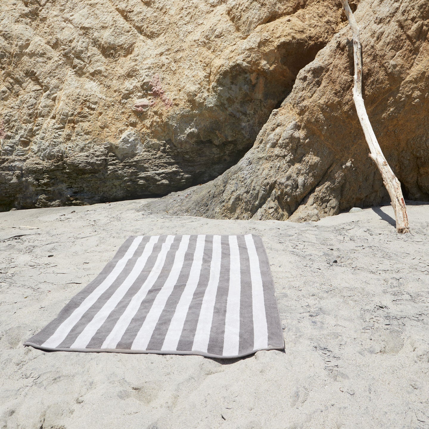 A striped light grey and dark grey terry bath towel at the beach.
