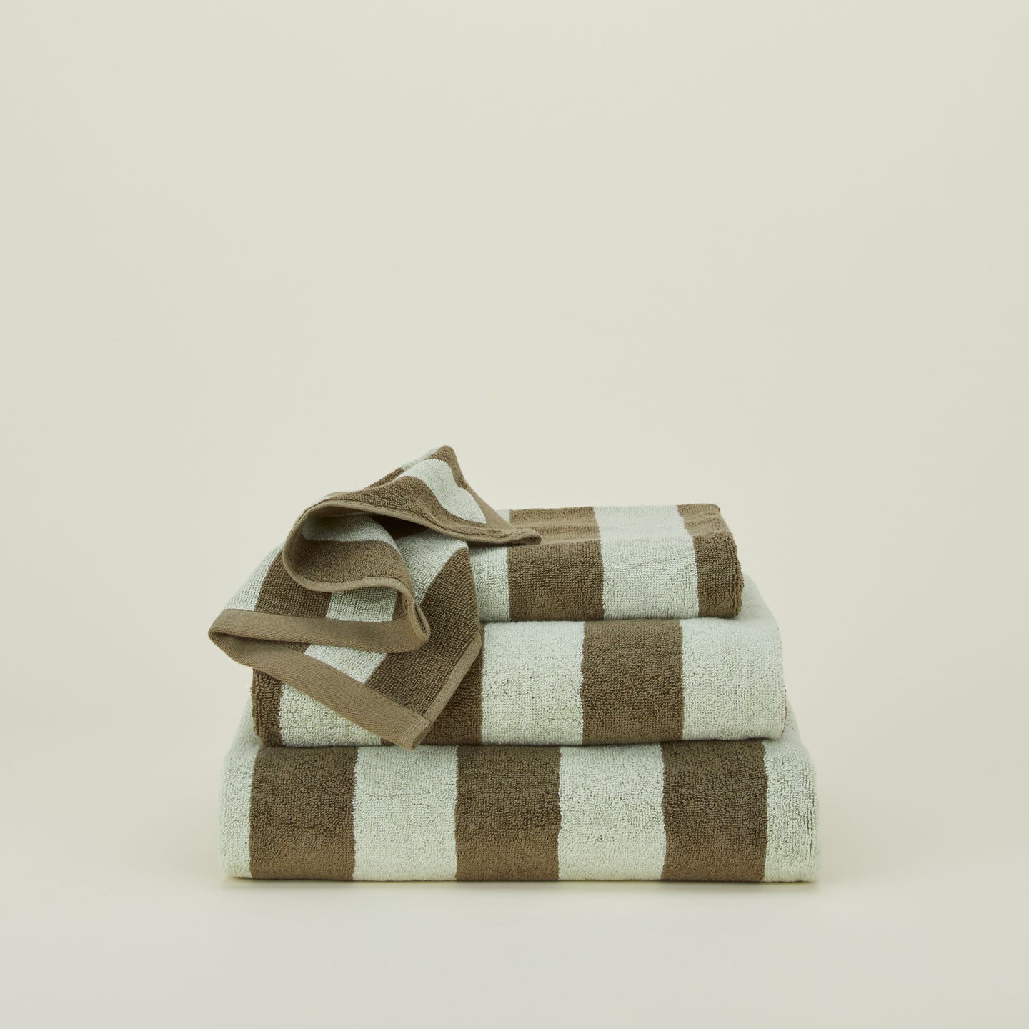 A stack of striped olive and sage terry towels in various sizes.