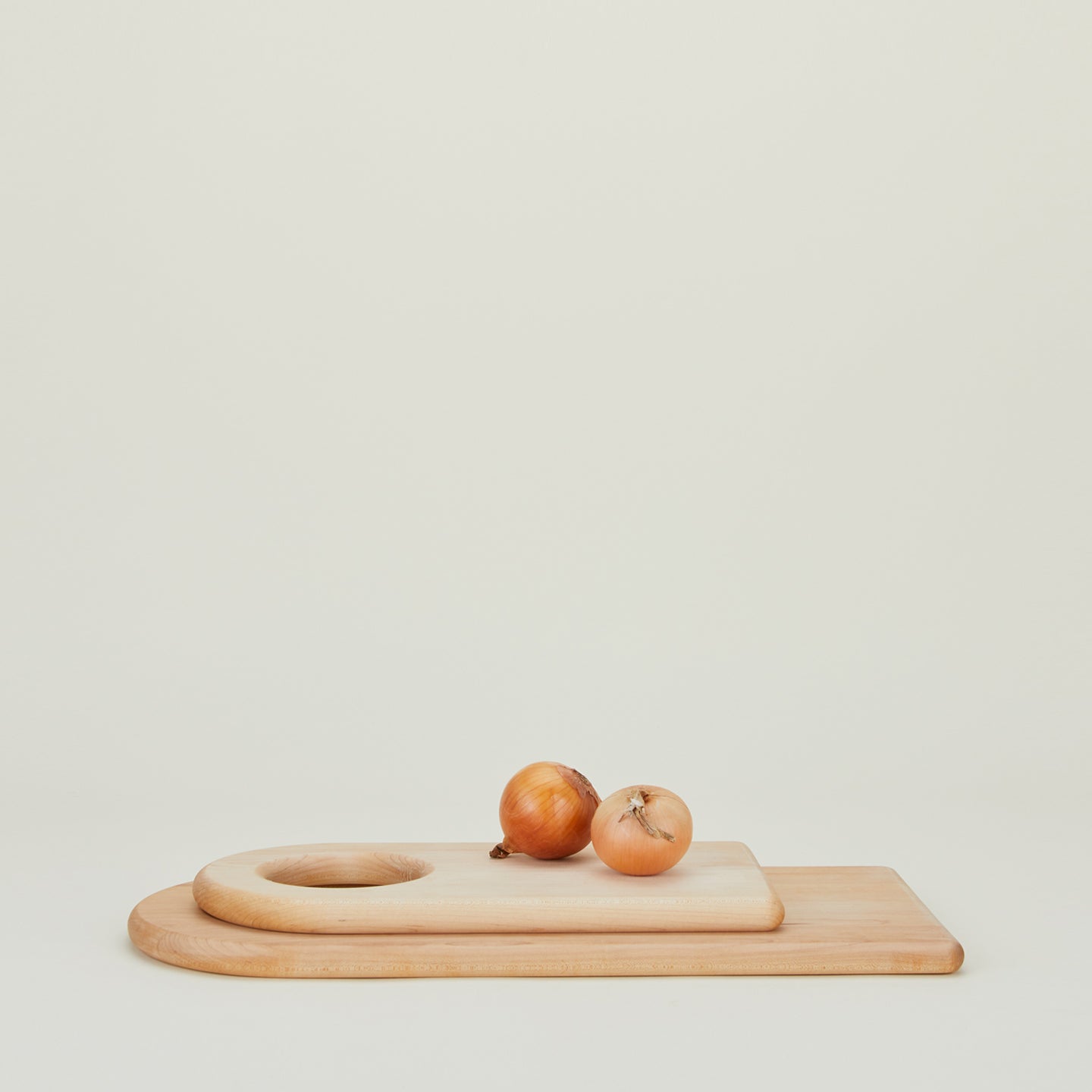 Large and small stacked arched cutting boards with onions