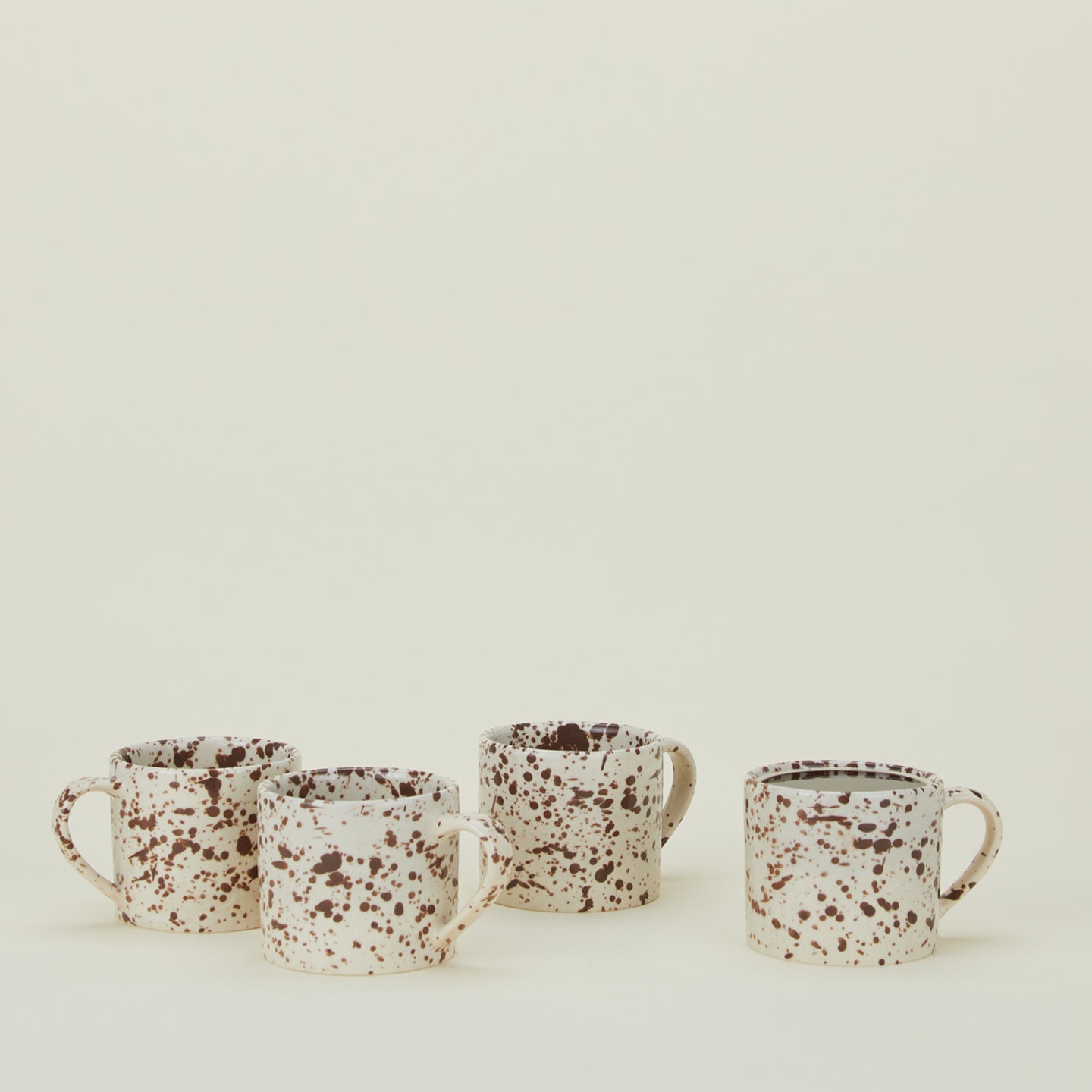 Set of four white mugs with cacao brown splatter glaze.