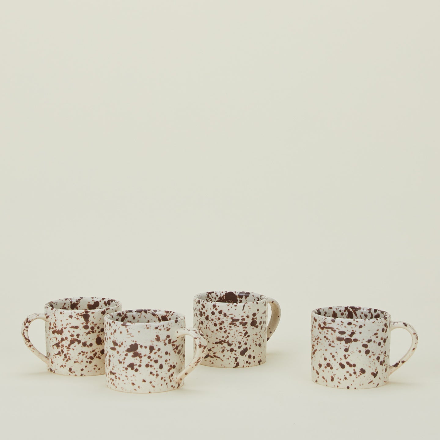 Set of four white mugs with cacao brown splatter glaze.