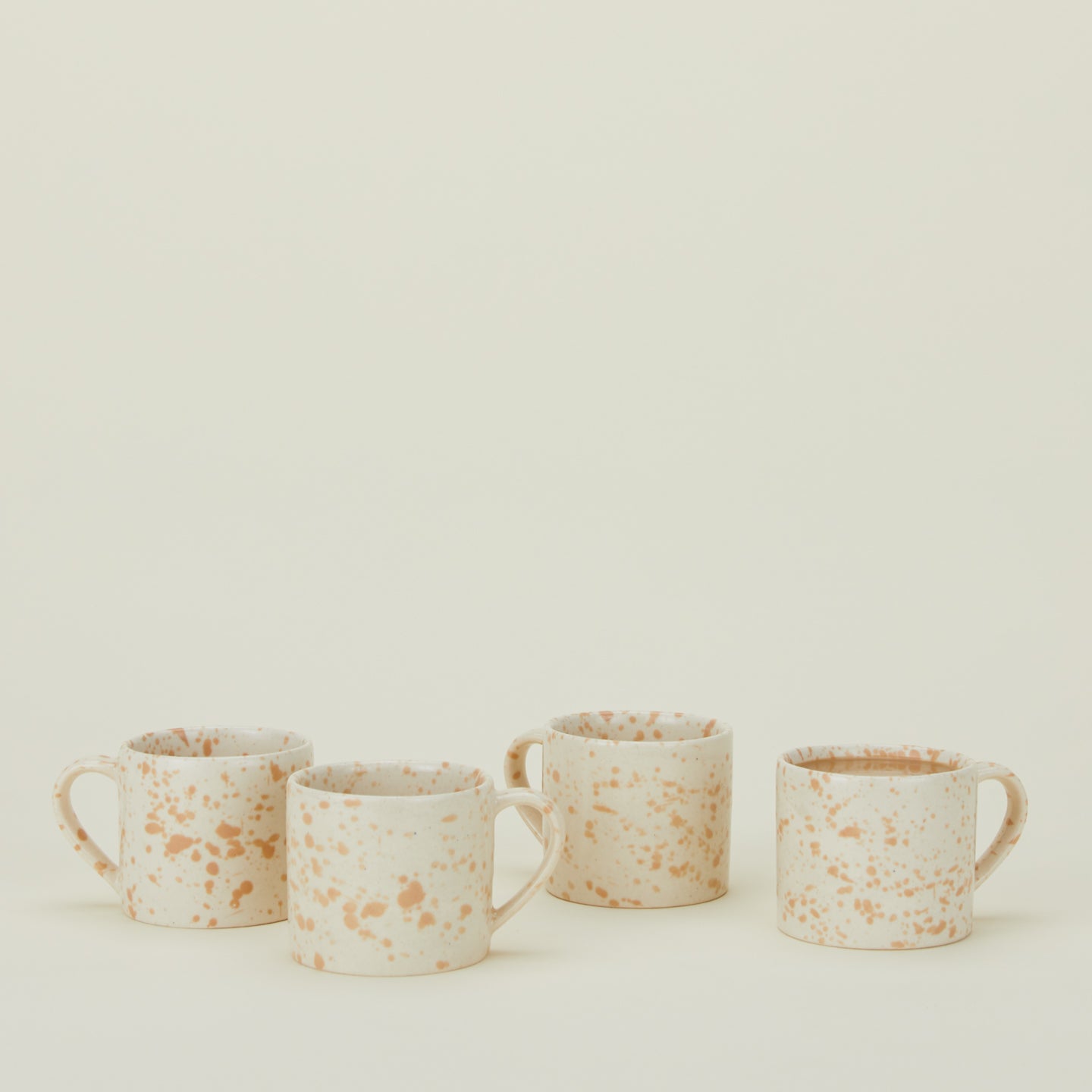 Set of four white mugs with latte light brown splatter glaze.