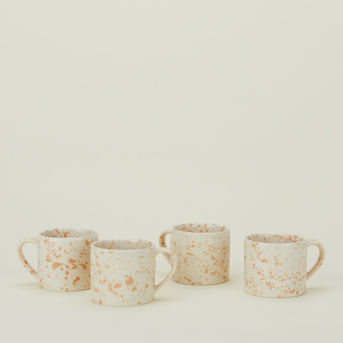 Set of four white mugs with latte light brown splatter glaze.