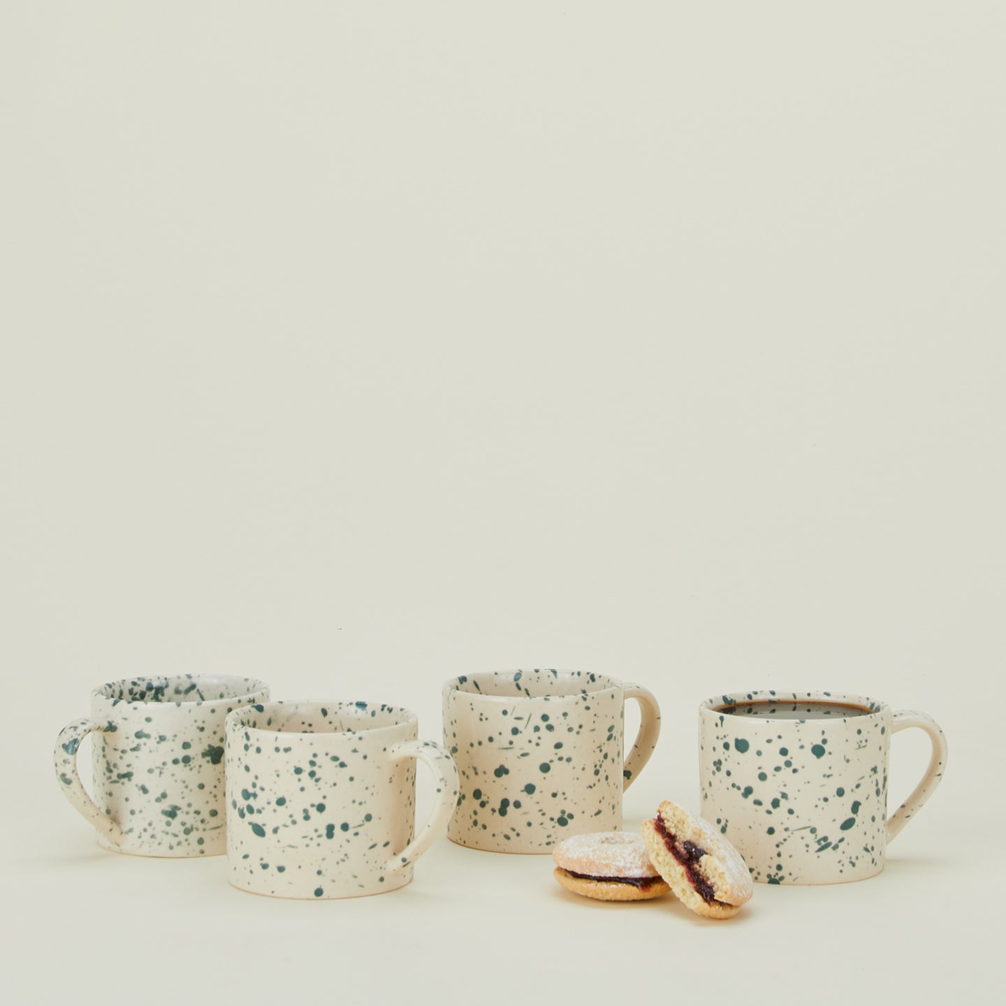 Set of four Splatterware mugs in Pool with coffee and cookies.