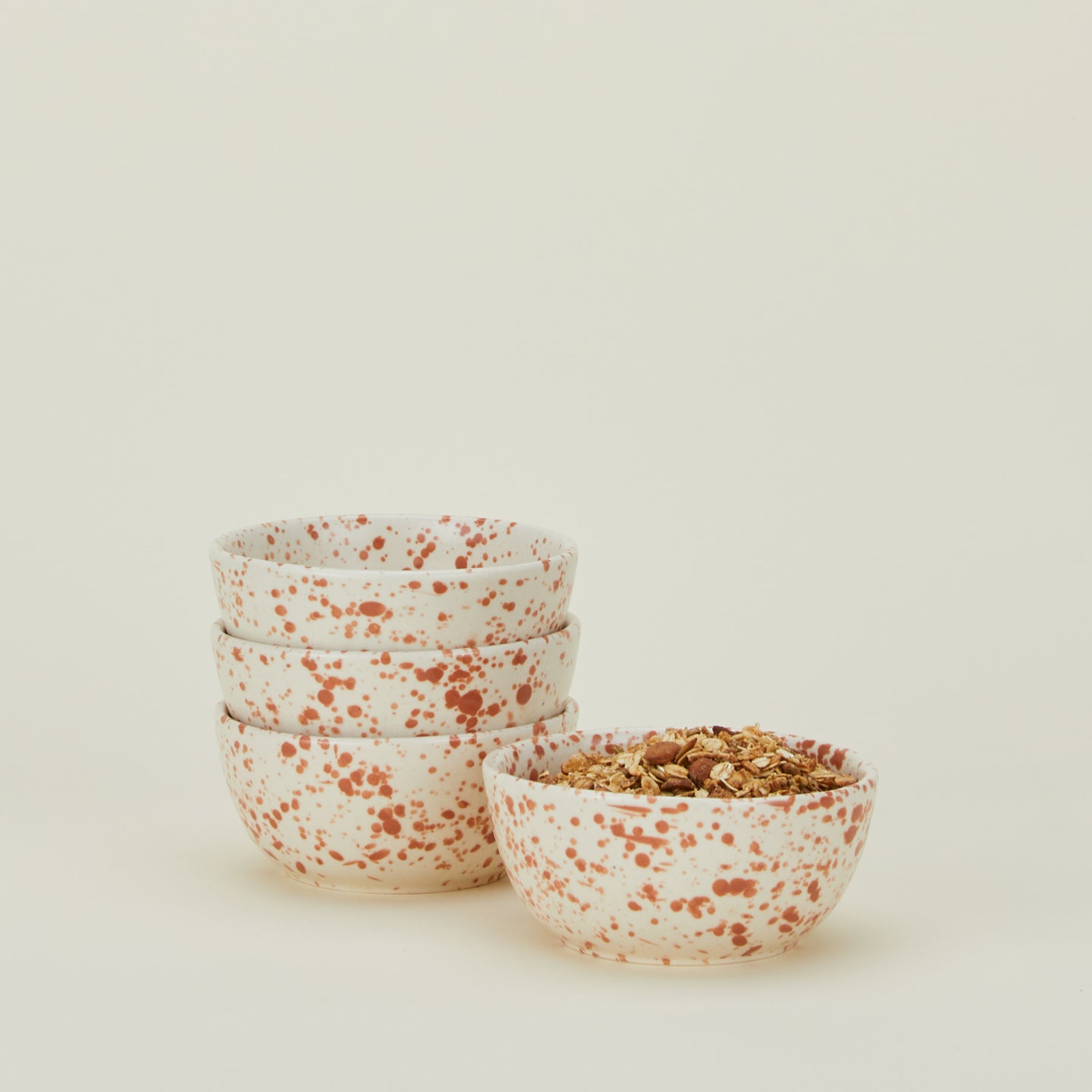 Set of four white bowls with terracotta orange splatter glaze.