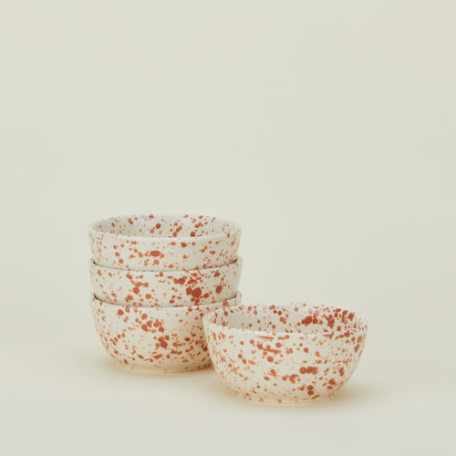 Set of four white bowls with terracotta orange splatter glaze.